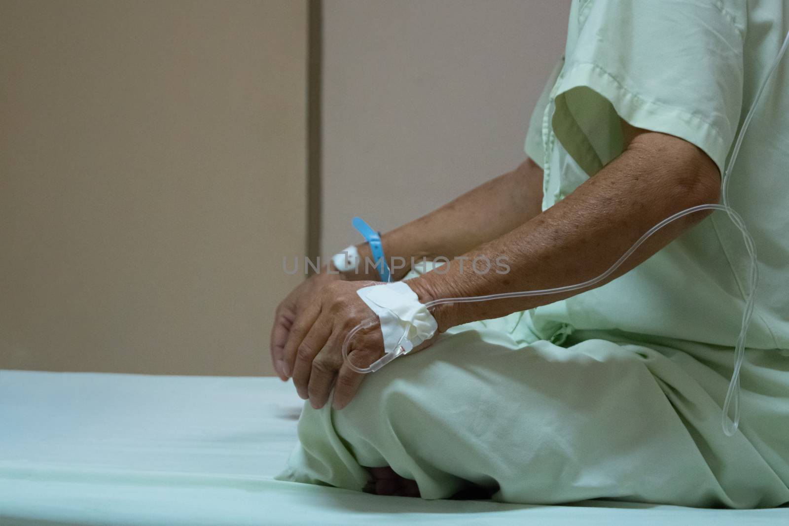 Patient asian elder man 70s with saline intravenous at C-line or A-line on a elderly patient hand on patient bed in intensive care unit (ICU.) room at hospital.