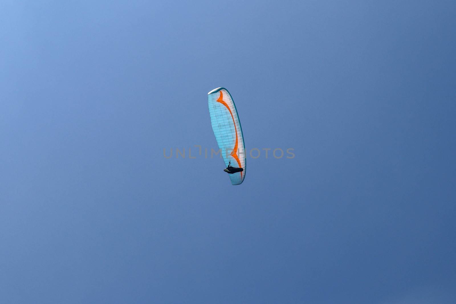 Paragliding in the sky. Paraglider flying in bright sunny day. Beautiful paraglider in flight on a turquise background. Concept of active lifestyle and extreme sport adventure. Isolated.