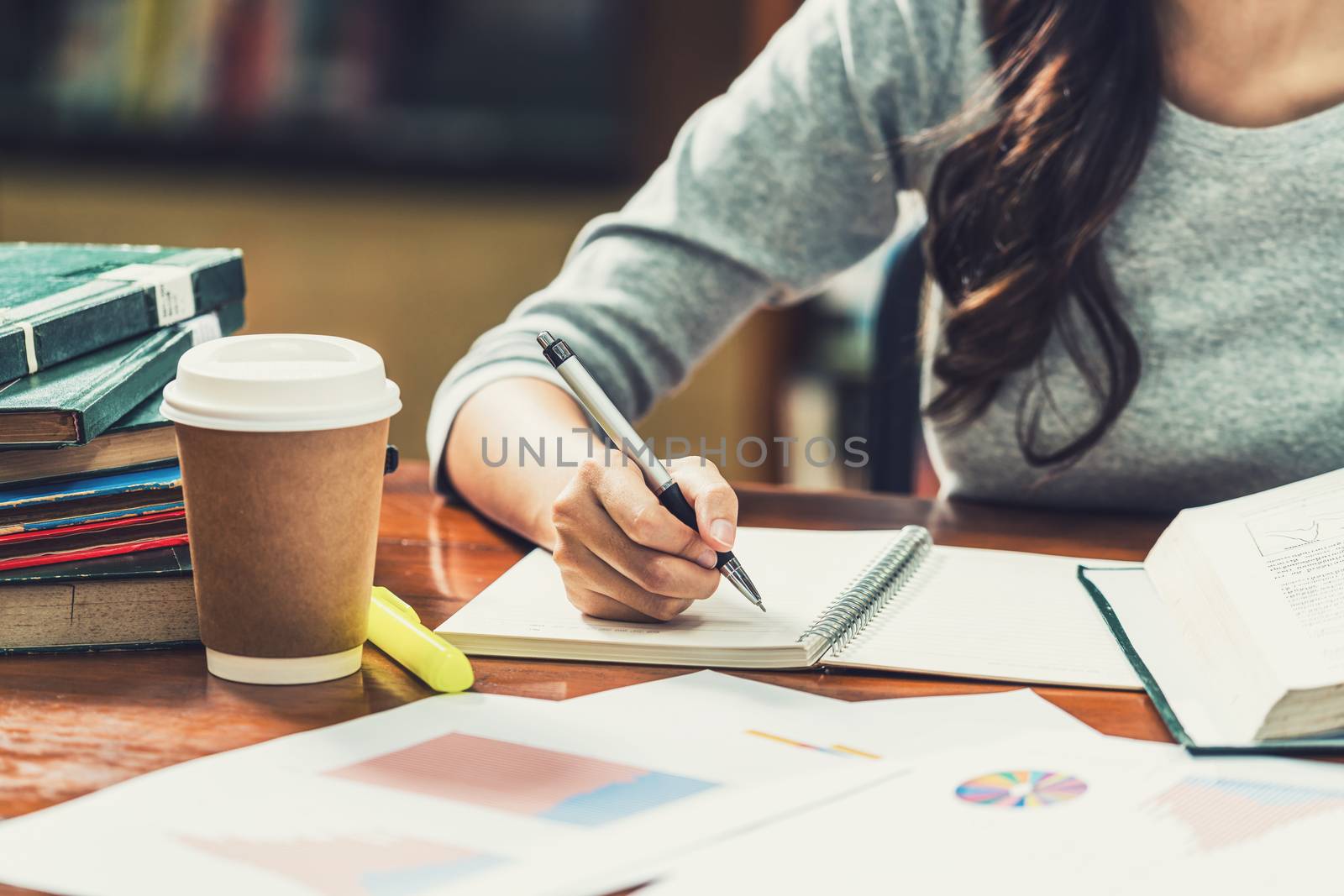 Closeup Asian young Student hand writing homework in library of by Tzido