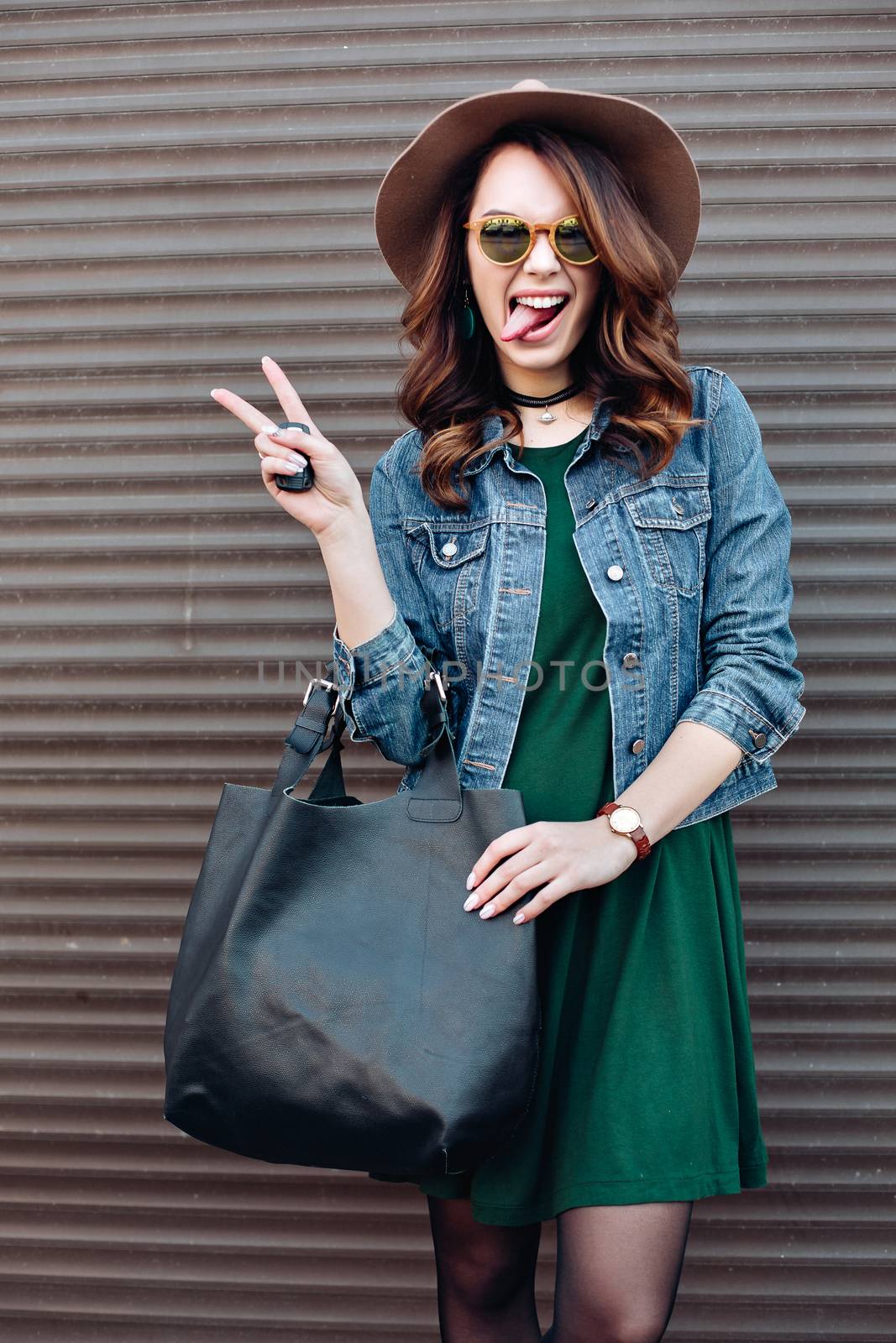 Stylish brunette in sunglasses and hat posing at street. by StudioLucky