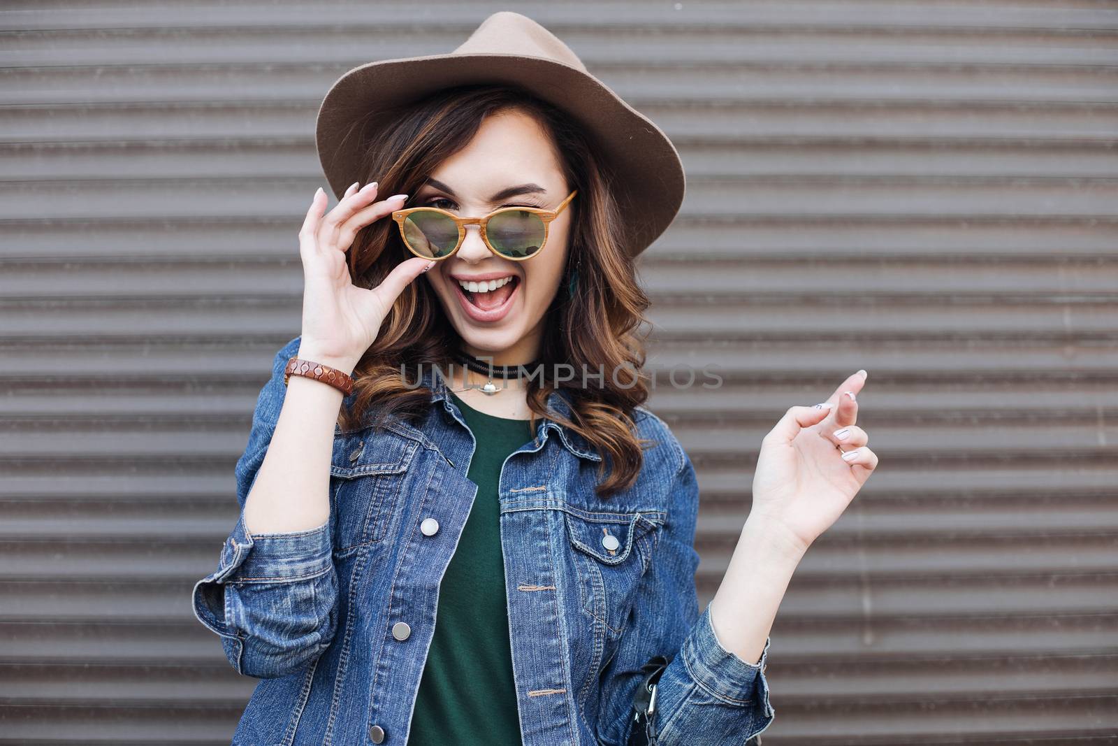 Romantic and beautiful brunette girl in brown hat lokking at camera and posing at street. Attractive woman with wavy hair, perfect make up, walking after beauty salon. Street fashion.