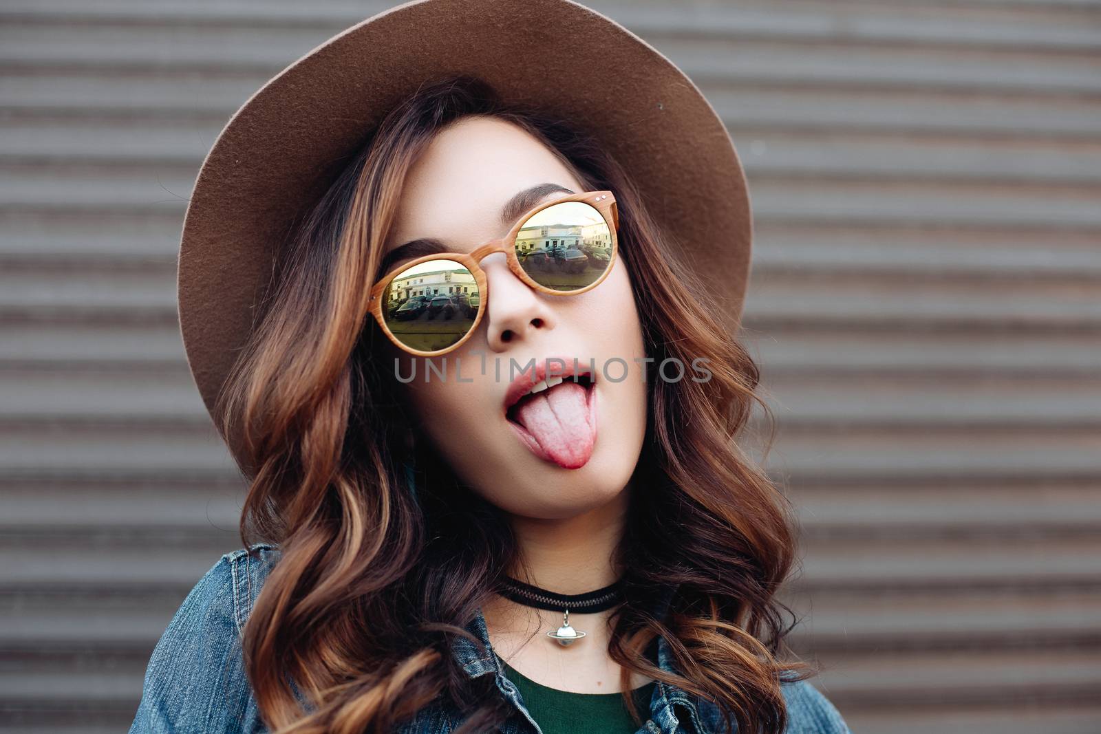 Romantic and beautiful brunette girl in brown hat lokking at camera and posing at street. Attractive woman with wavy hair, perfect make up, walking after beauty salon. Street fashion.