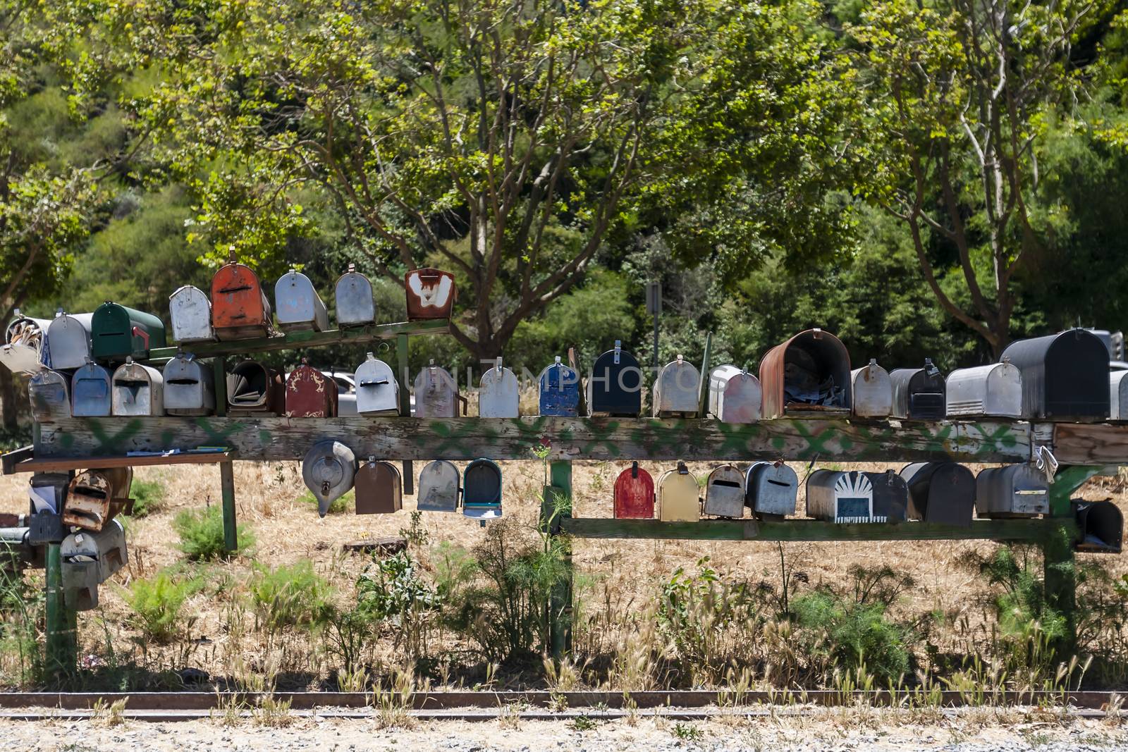 Colorful antique mailboxes sit on a roadside intersection