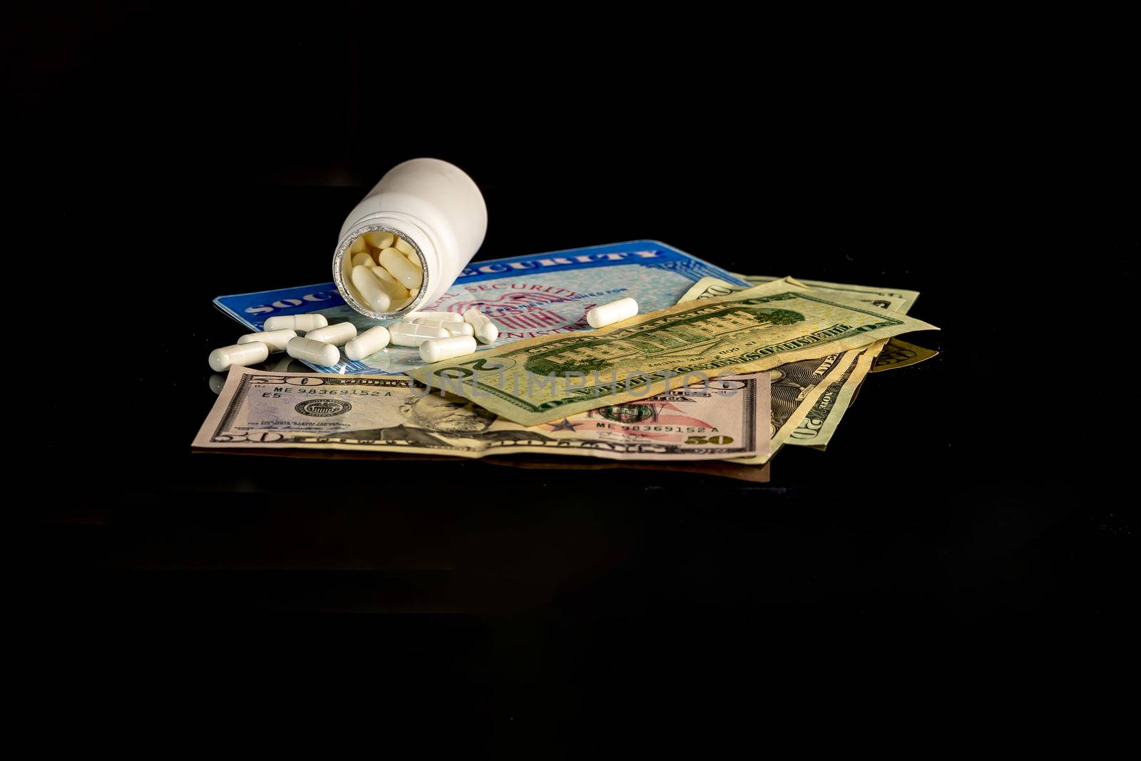 A bottle of pills on top of a blank social security card surrounded by American money