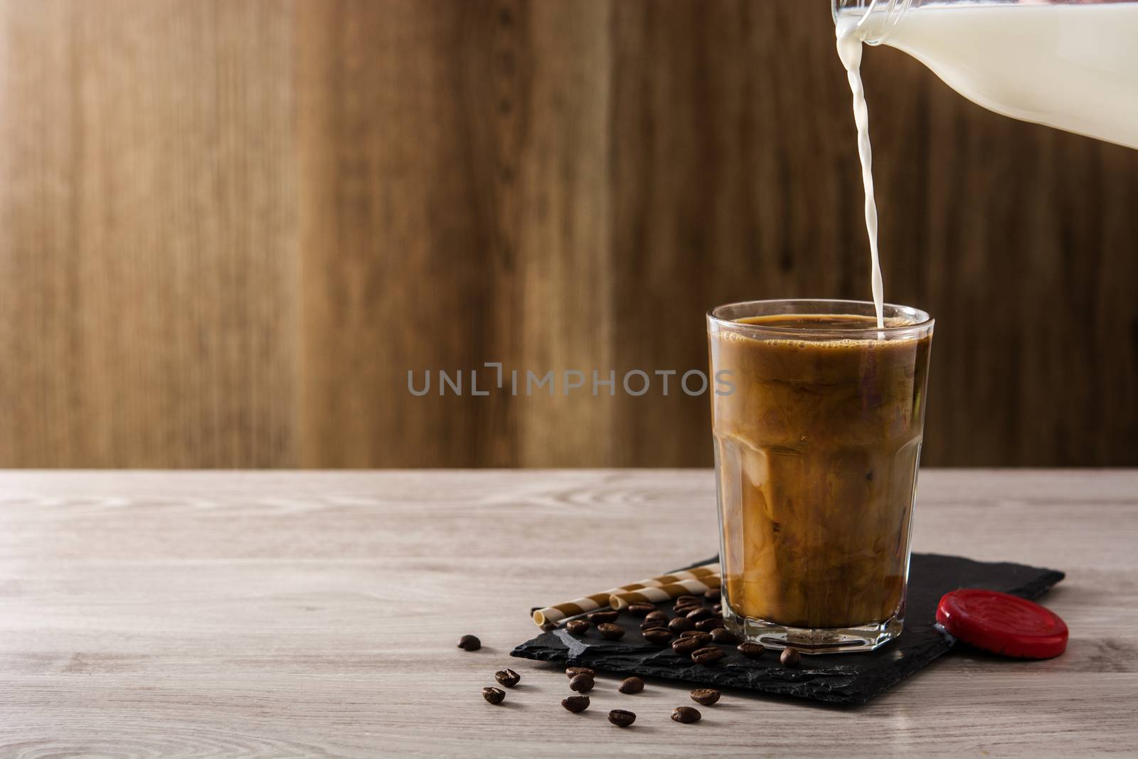 Preparing iced coffee or caffe latte on wooden table