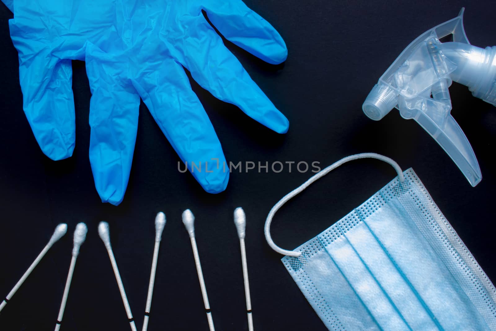 A close up of medical items: throat swabs, gloves, medical face mask and spray disinfecting liquid spray on a black background. by oasisamuel