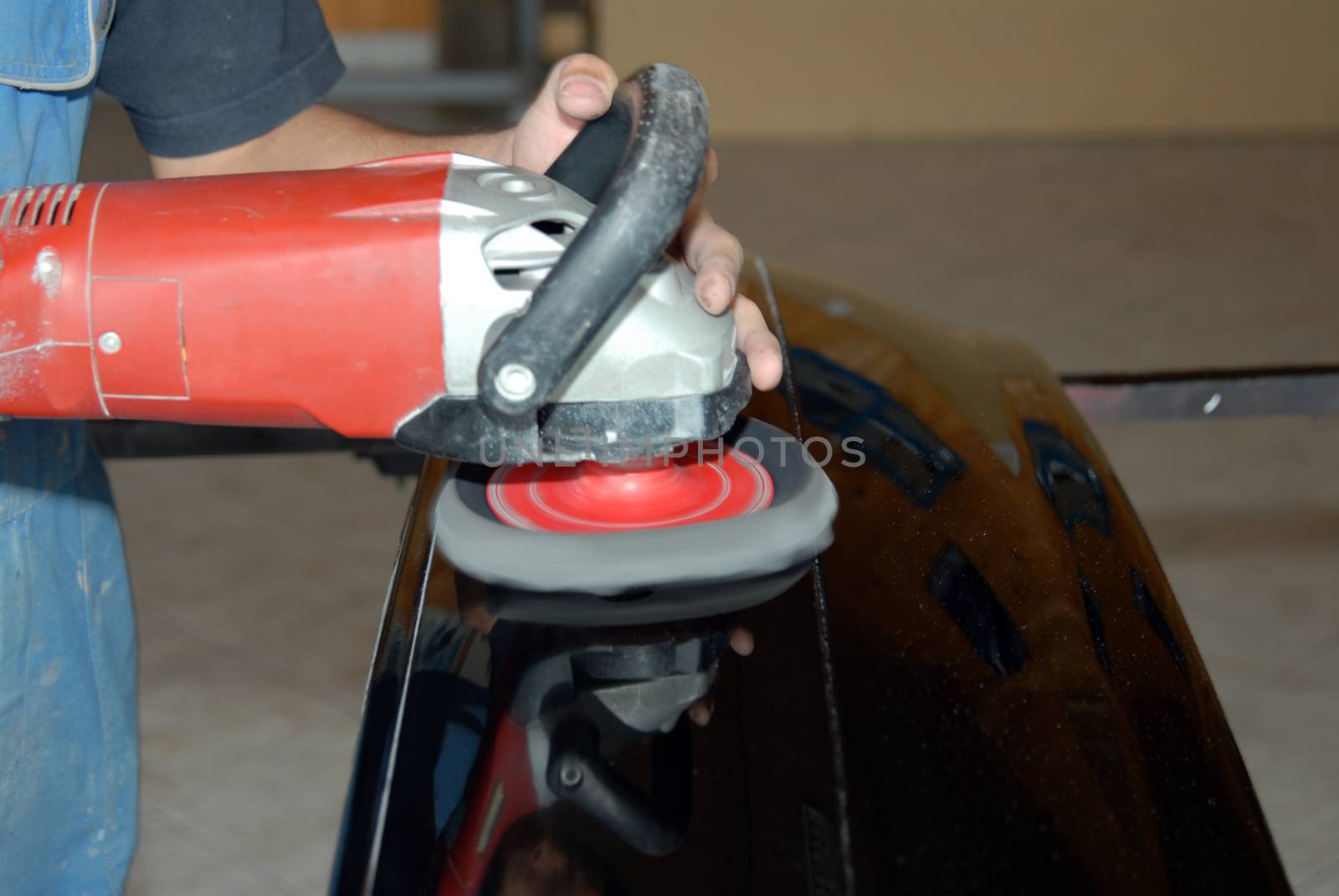Partial view of a man holding an electric machine for polishing cars