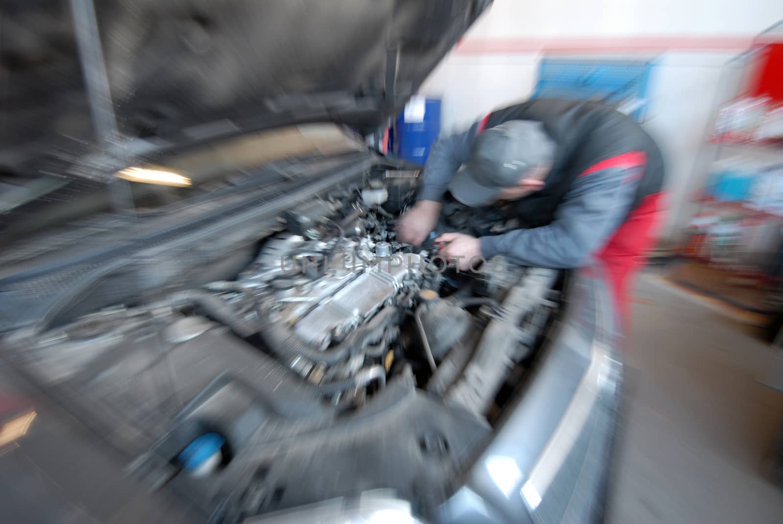 An auto mechanic works on an engine of an automobile in an auto repair shop