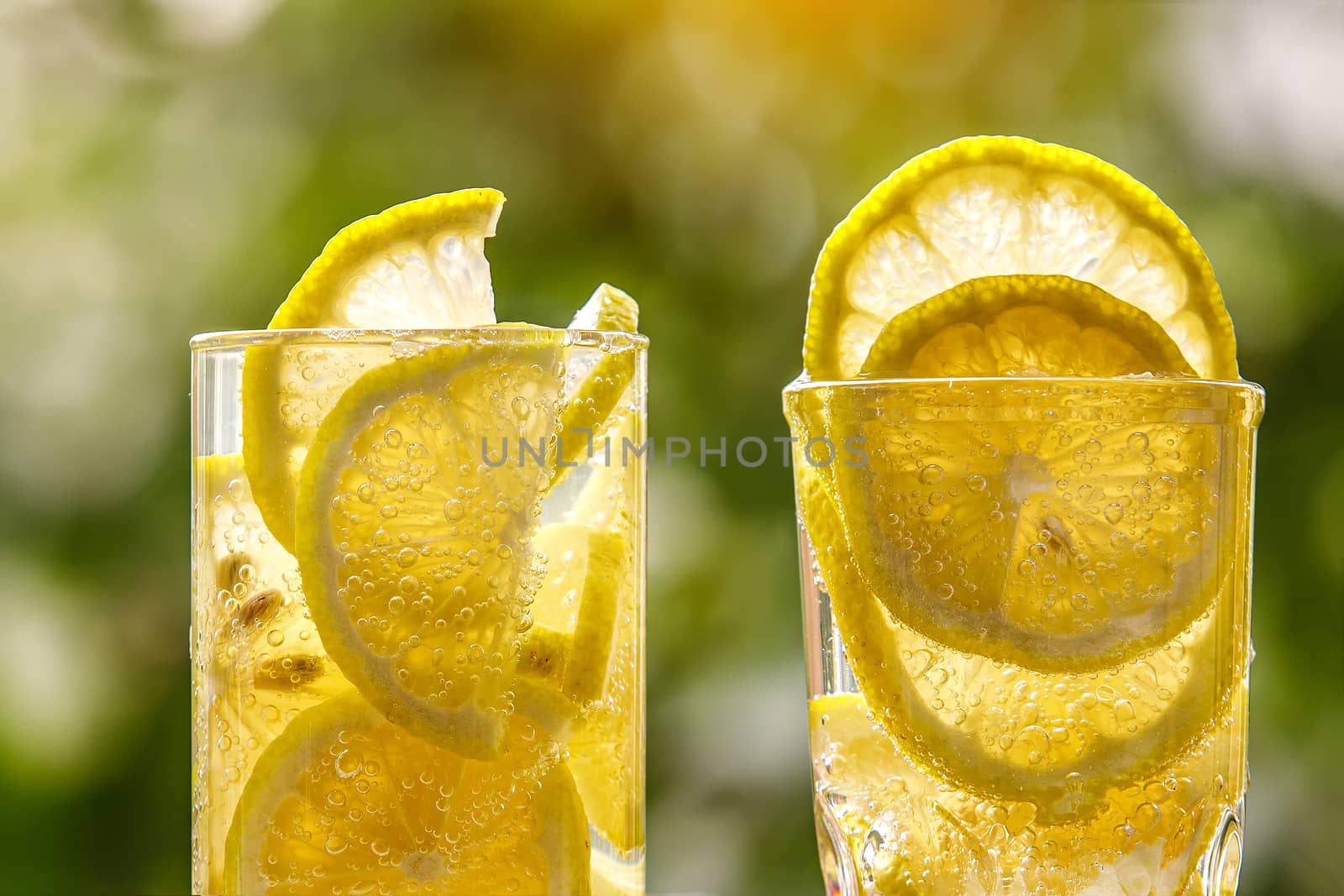 Glass of lemon water on the sunny garden background. Close-up view. by 9parusnikov