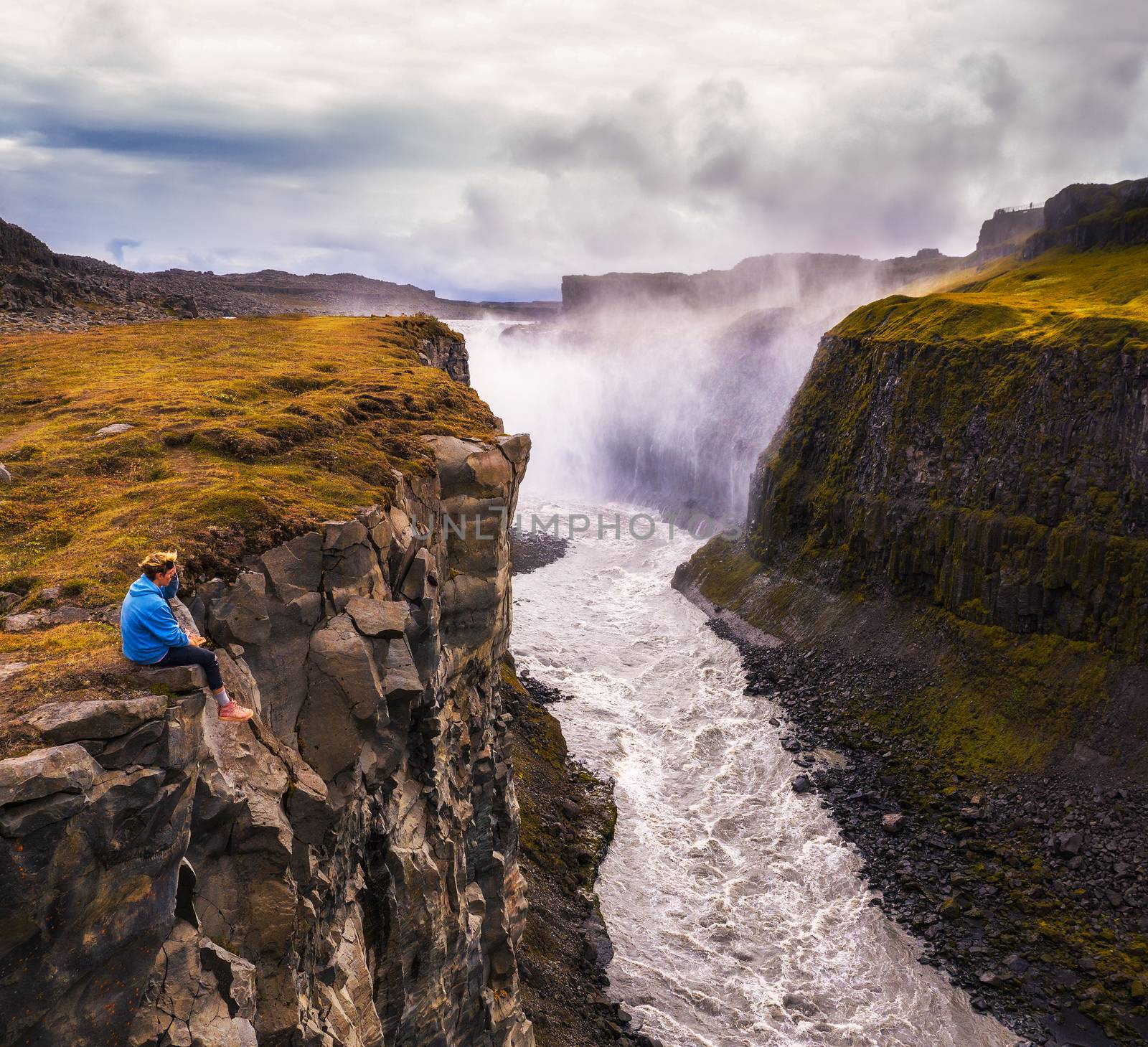 Hiker sitting at the edge of the Gullfoss waterfall in Iceland by nickfox