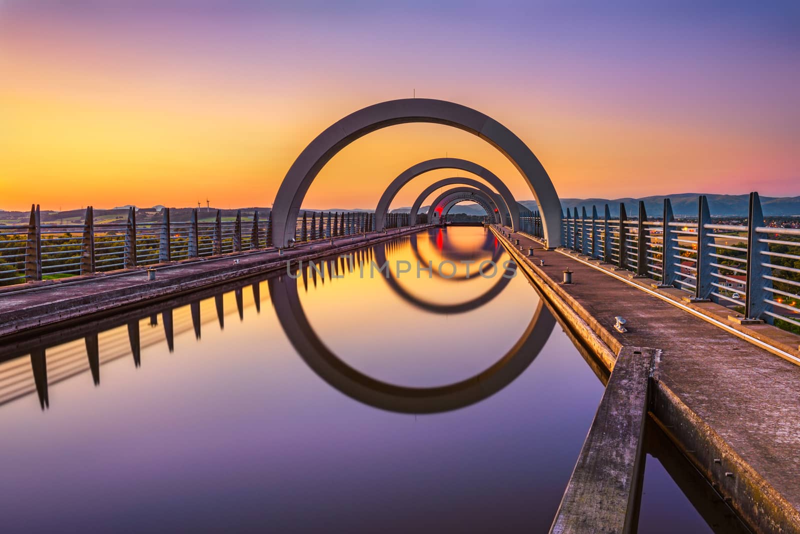 Falkirk Wheel at sunset. Falkirk Wheel is a rotating boat lift in Scotland and connects the Forth and Clyde Canal with the Union Canal. Long exposure.