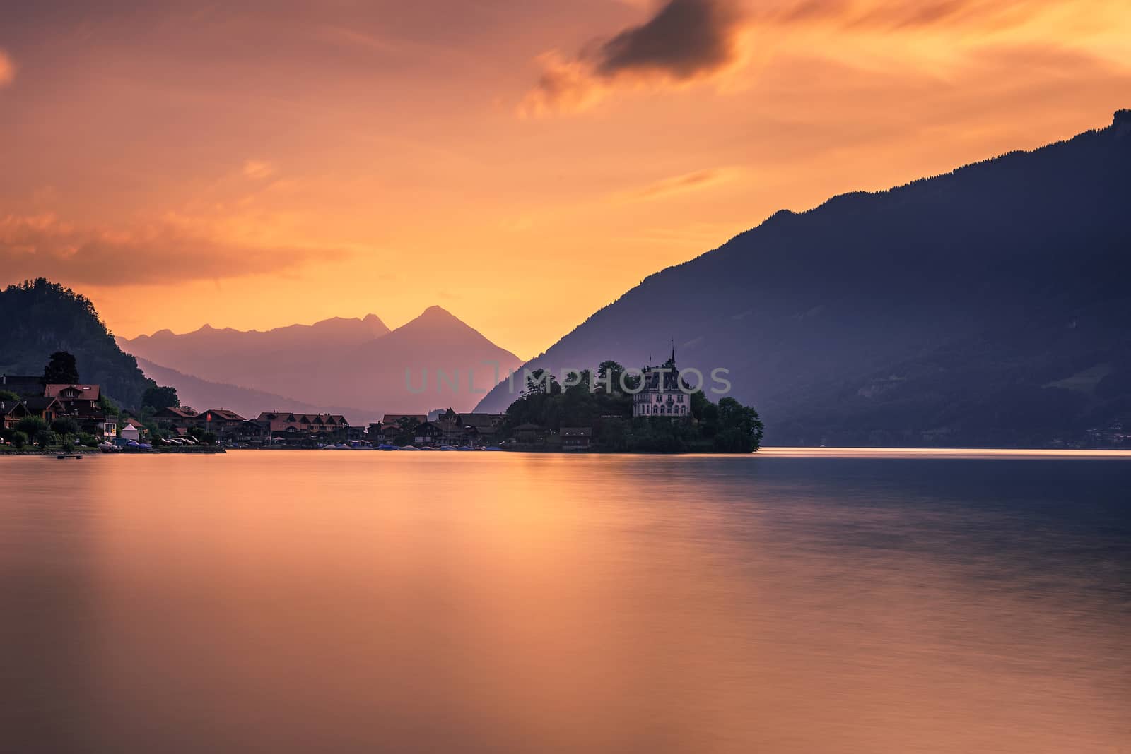 Sunset above Iseltwald peninsula and former castle in Switzerland by nickfox