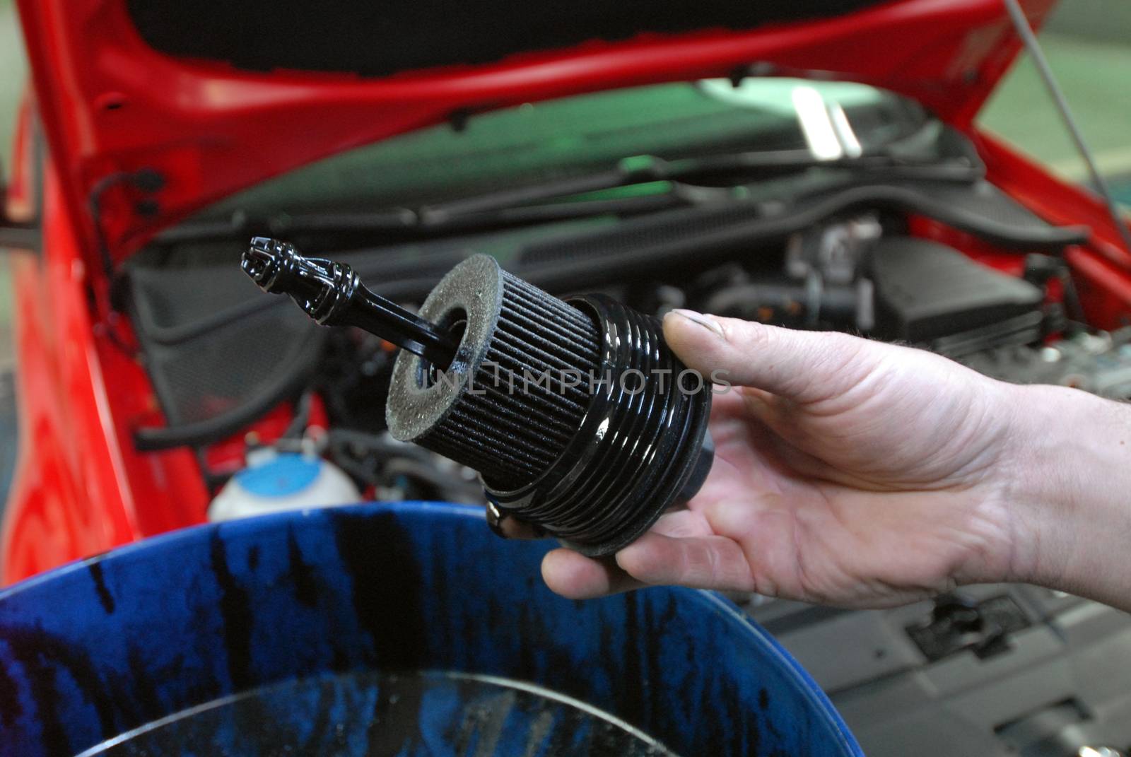 Repairman holding the old oil filter by car