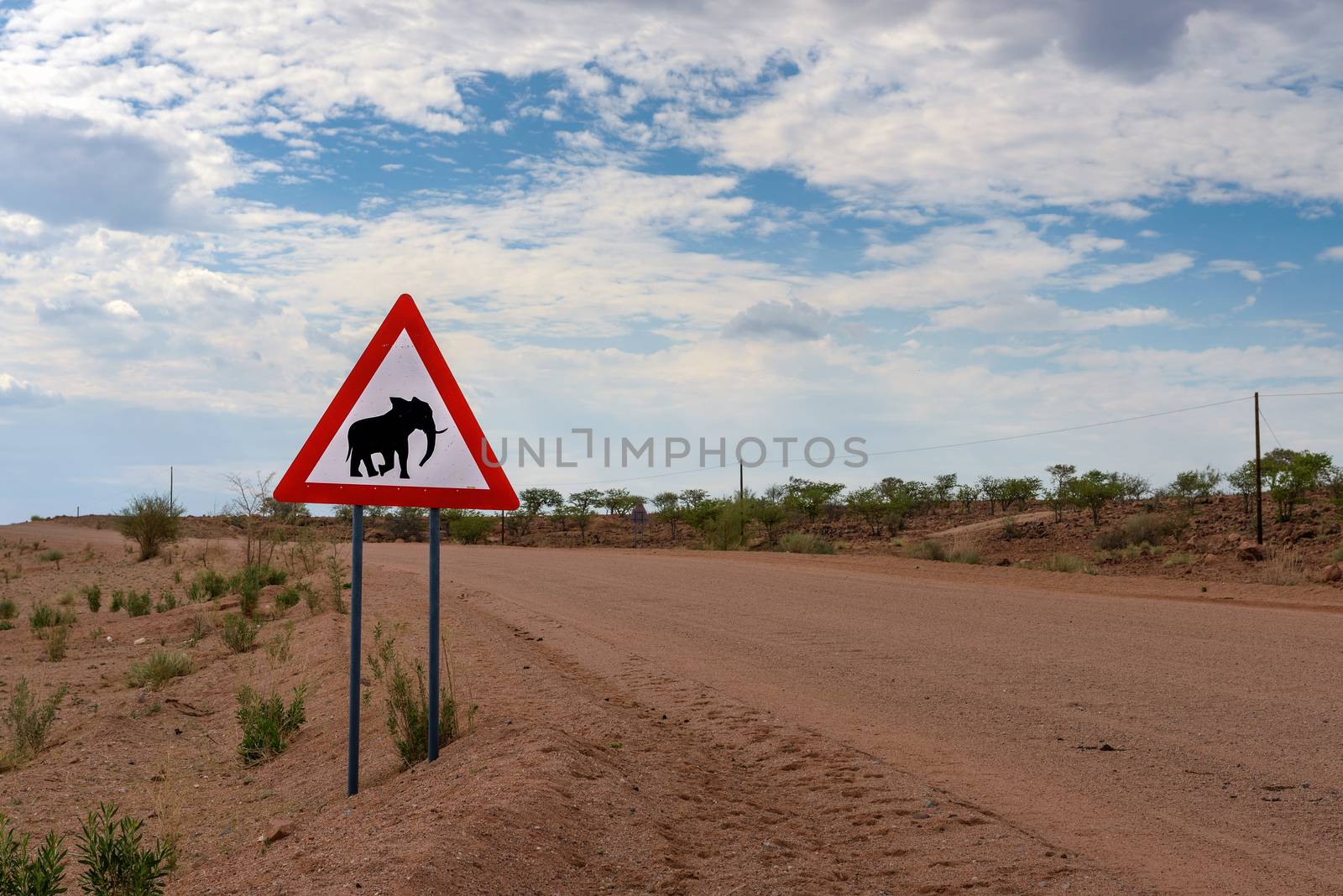 Elephant crossing warning road sign placed by a gravel road in the desert of Namibia.