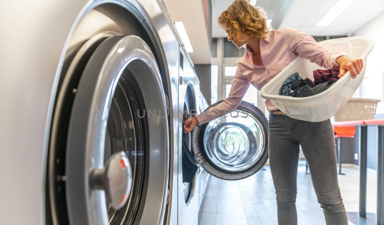 inserting dirty clothes into the washing machine in the laundry room by Edophoto