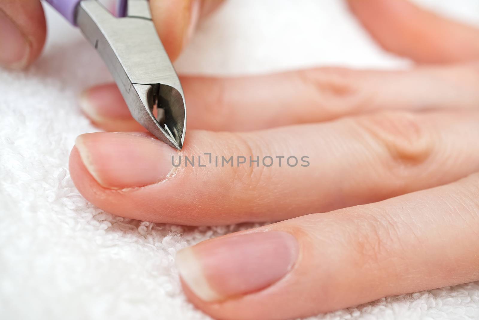 Nail Salon. Manicure process in beauty salon or at home. Closeup Of Female Hand With Healthy Natural Nails Getting Nail Care Procedure. Closeup Hands Removing Cuticles With Professional Nail Tool