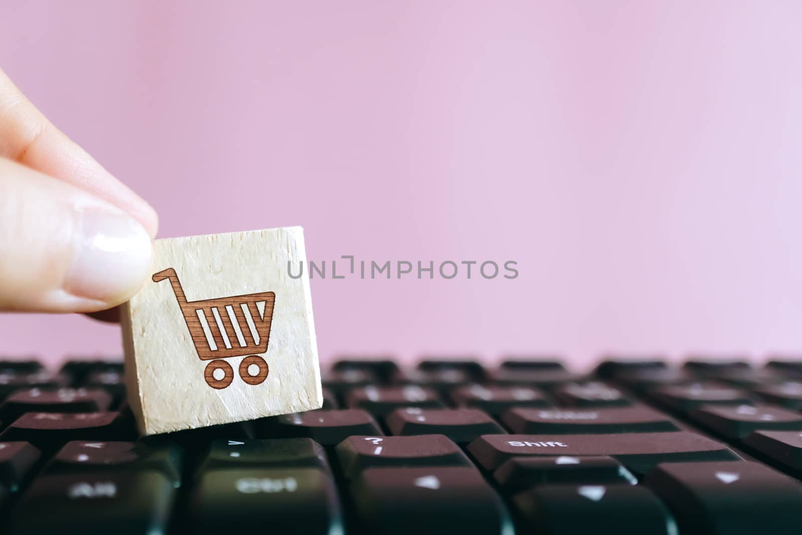 Closed up shopping cart icon on wood cube on computer keyboard. Online shoping business technology concept.