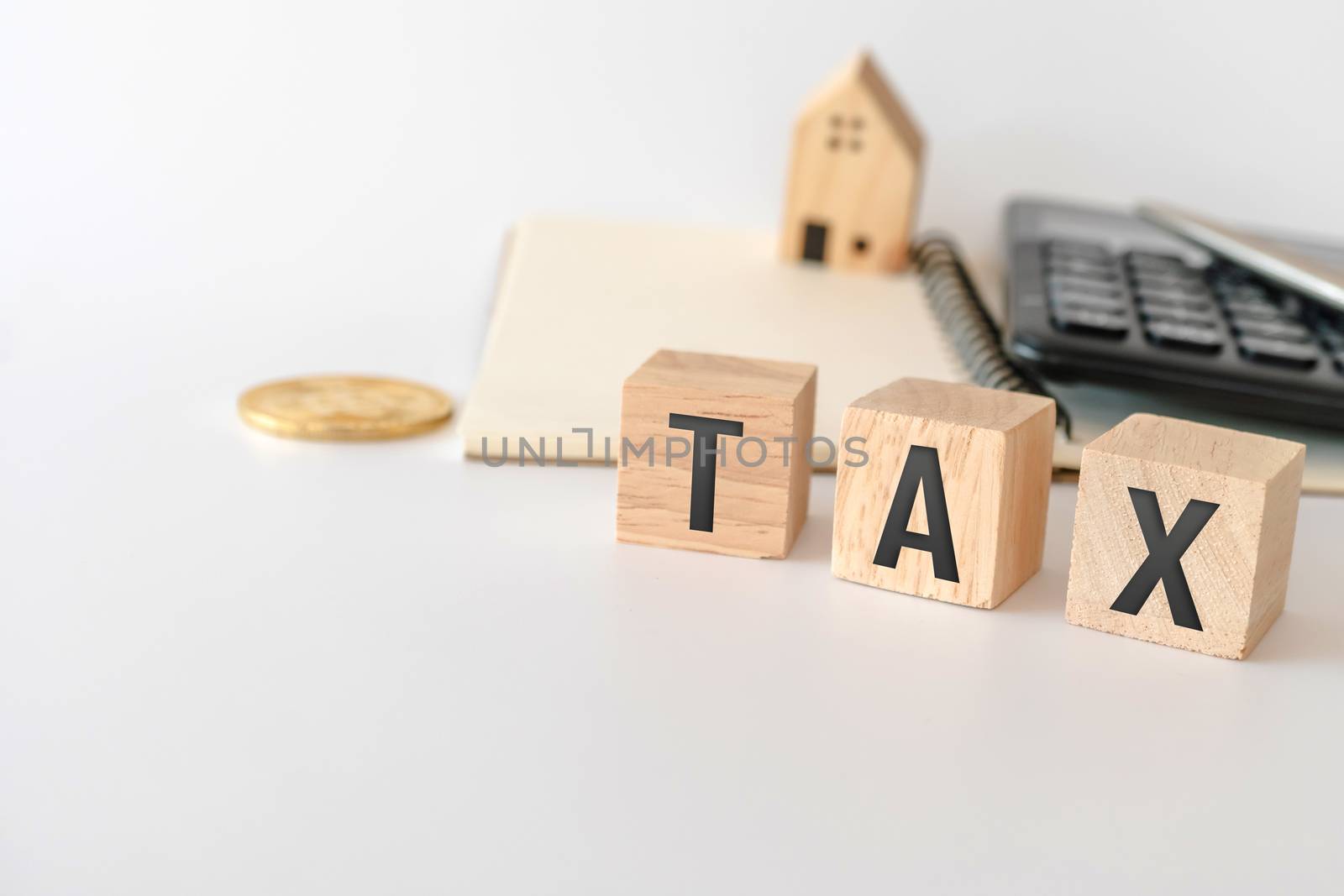 Tax word on wooden cube with objects as gold coin, calculator and mini home model behide white clean background. Business financial loan property concept.Tax word on wooden cube with objects as gold coin, calculator and mini home model behide white clean background. Business financial loan property. by Suwant