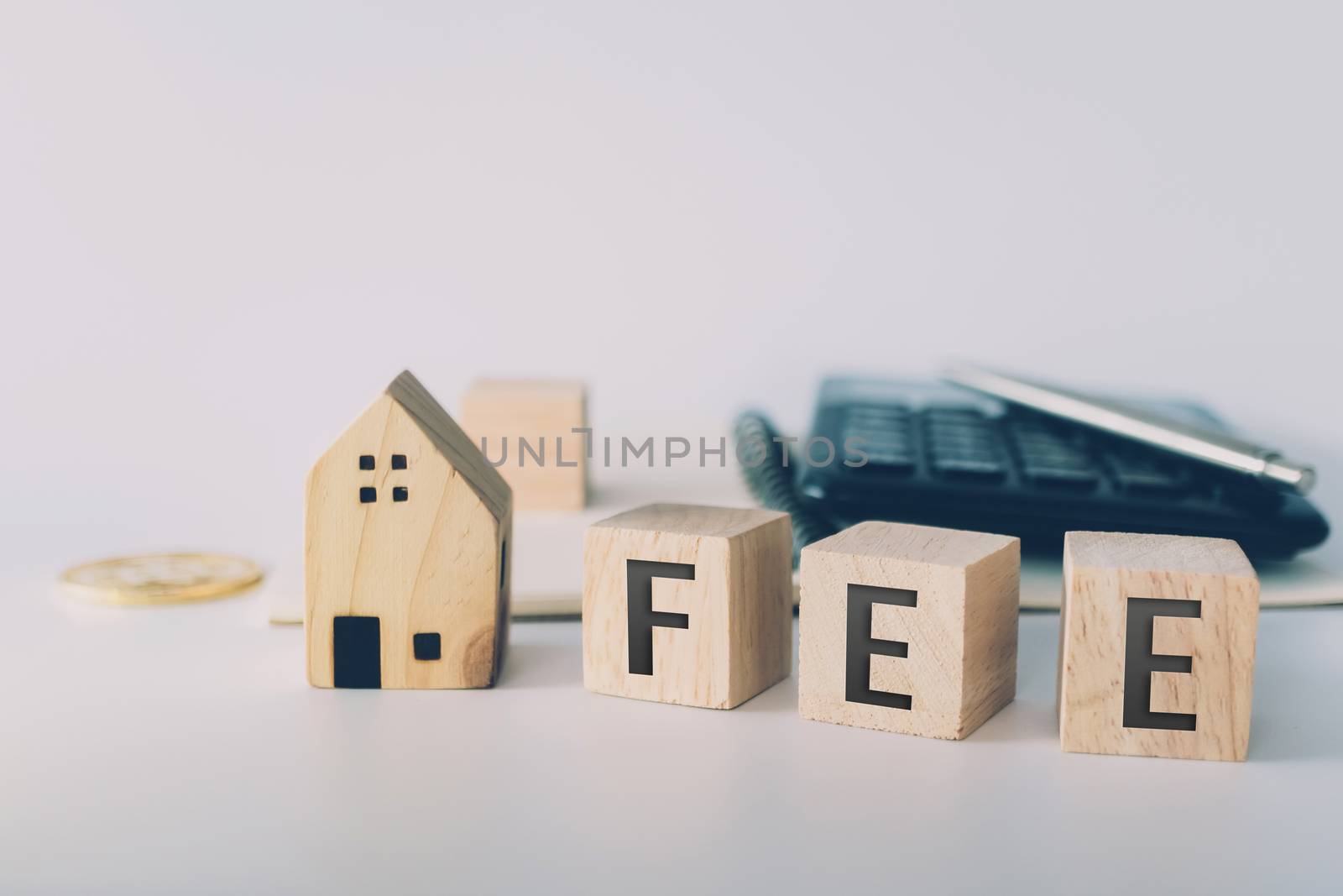 Tax word on wooden cube with objects as gold coin, calculator and mini home model behide white clean background. Business financial loan property concept.