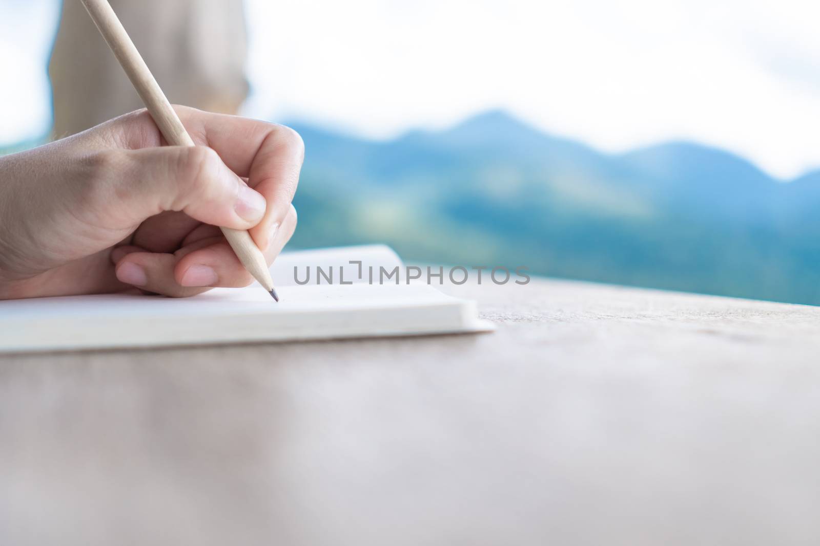 Woman hand writing down in small white memo notebook for take a note not to forget or to do list plan for future.