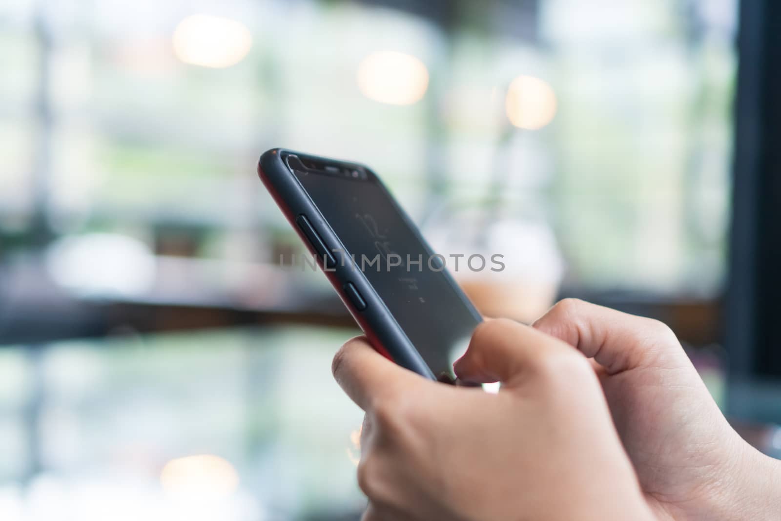 Womanhand using smartphone to do work business, social network, communication in public cafe work space area.