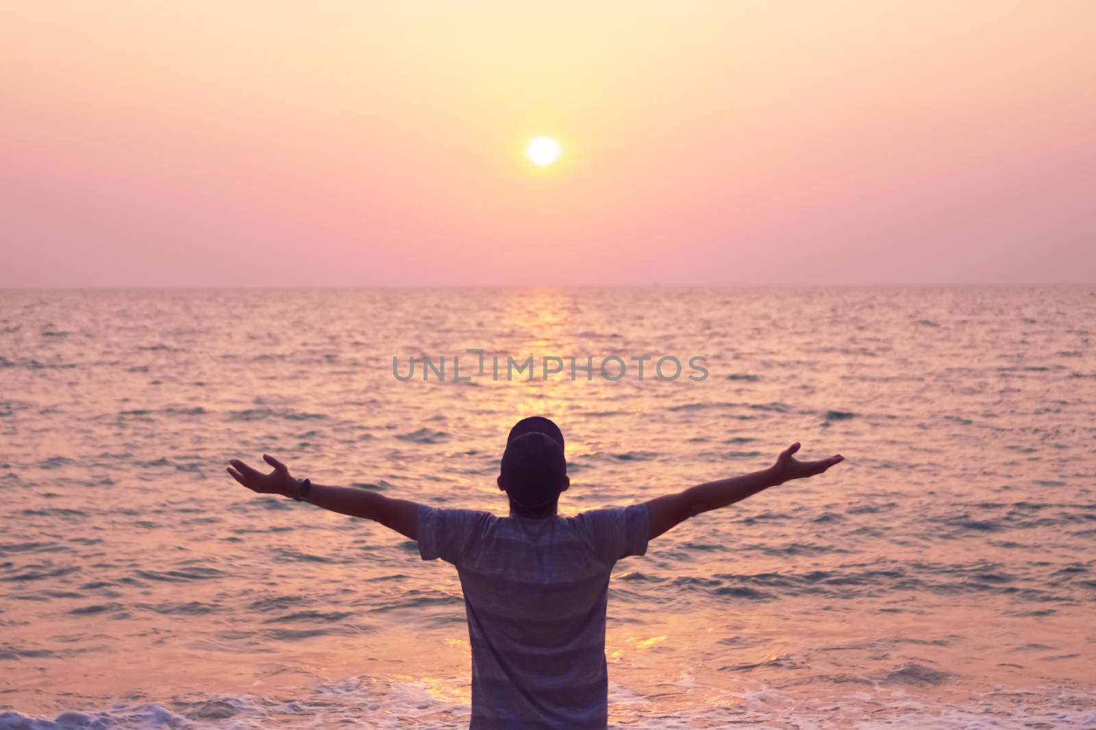 Man rise hands up to sky freedom concept with sunset sky and summer beach background.