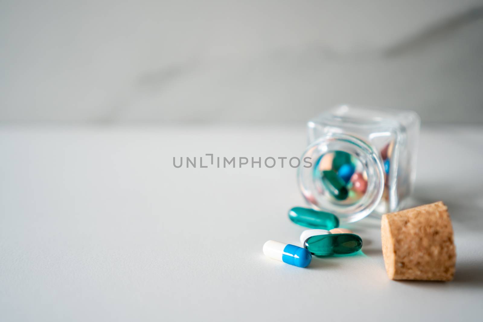 Top view of medicine tablets pour from pills bottle of marble texture white background. Health care medical lifestyle trend concept.