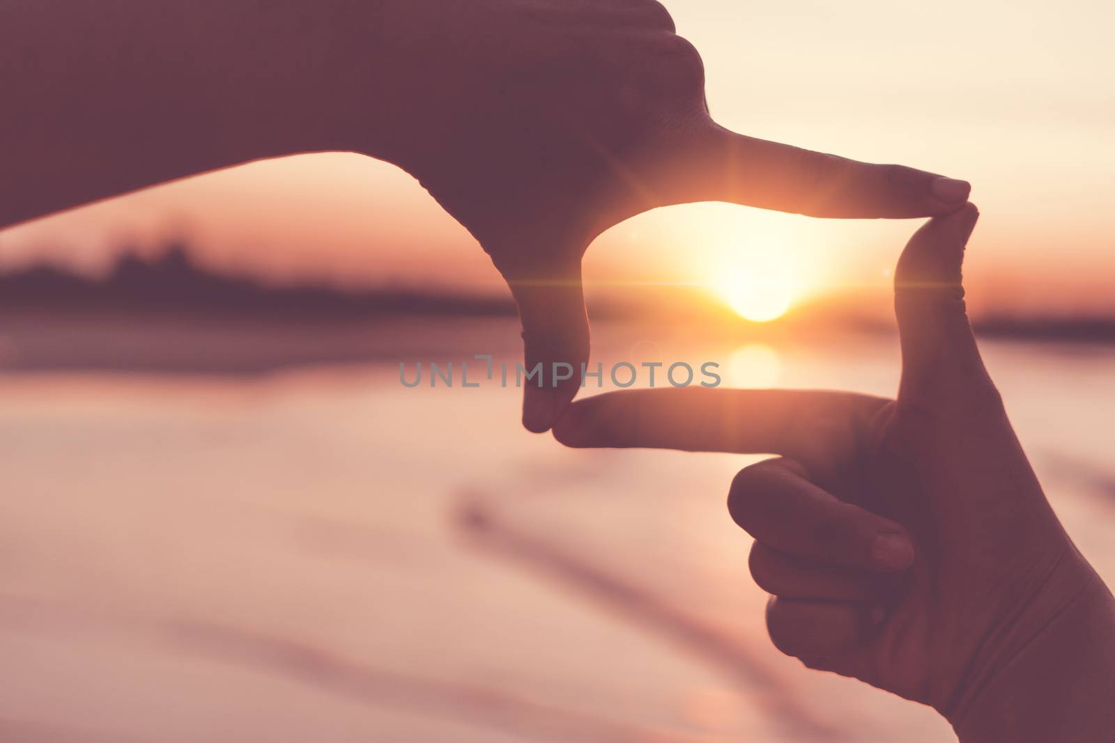 Selective focus of woman hands making frame by finger gesture with sunrise on mountain, Female capture sunrise or sunlight outdoor. Future planning concept.