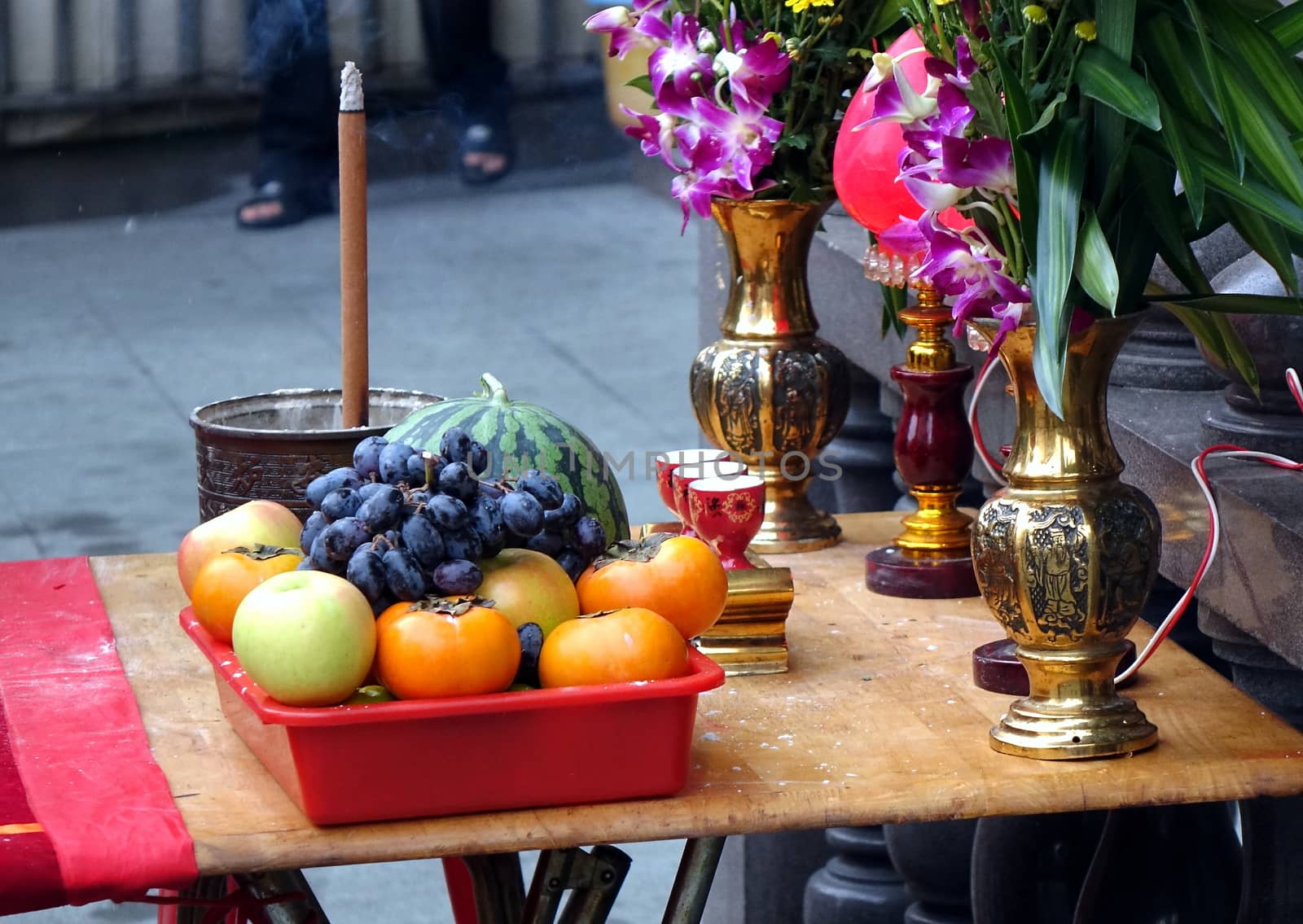 Buddhist worship table with fruits, wine, incense and flowers
