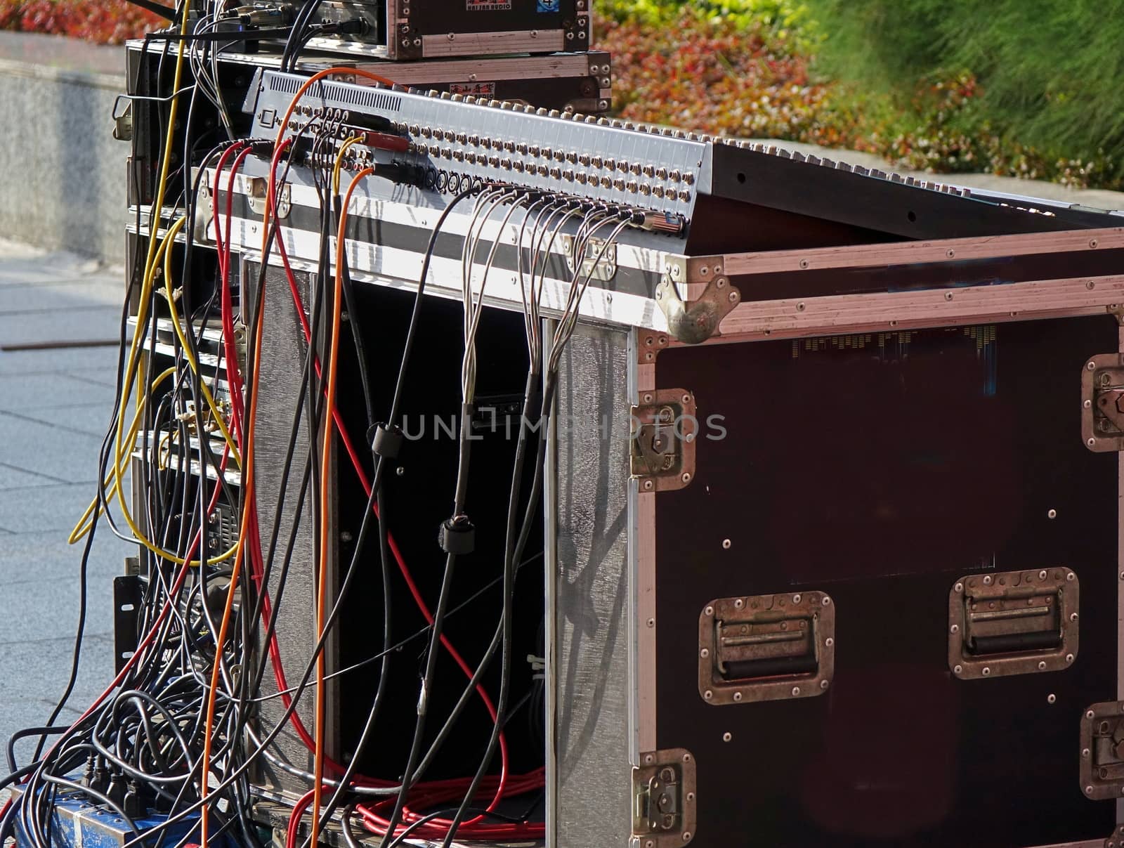 A large audio mixer console with a multitude of cables attached
