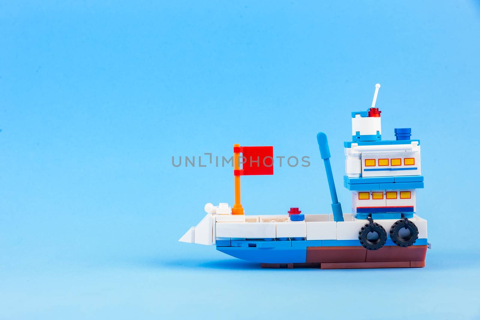 A fishing boat toy isolated on a blue background. by Bubbers