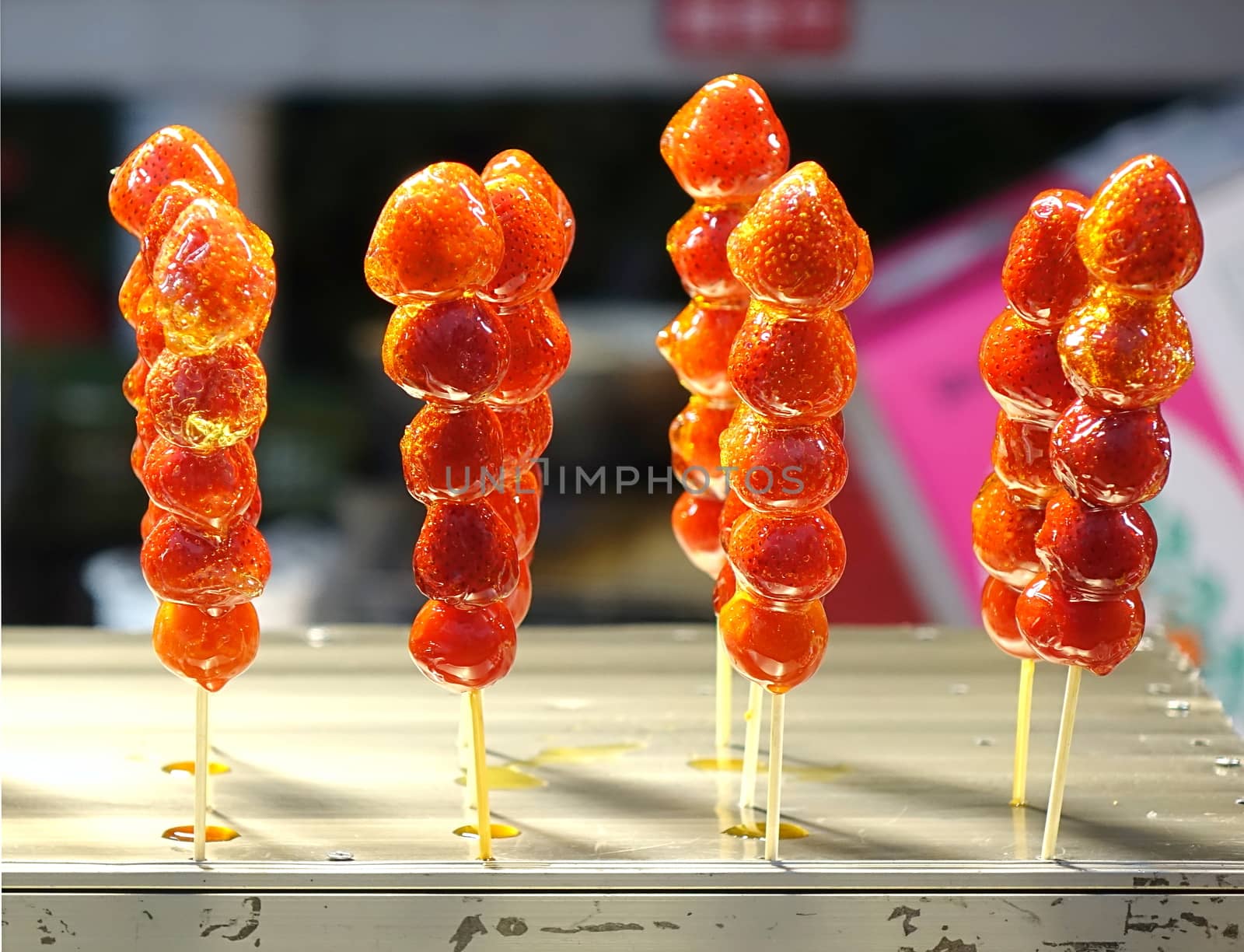 Strawberries glazed with sugar on skewers are sold at the market
