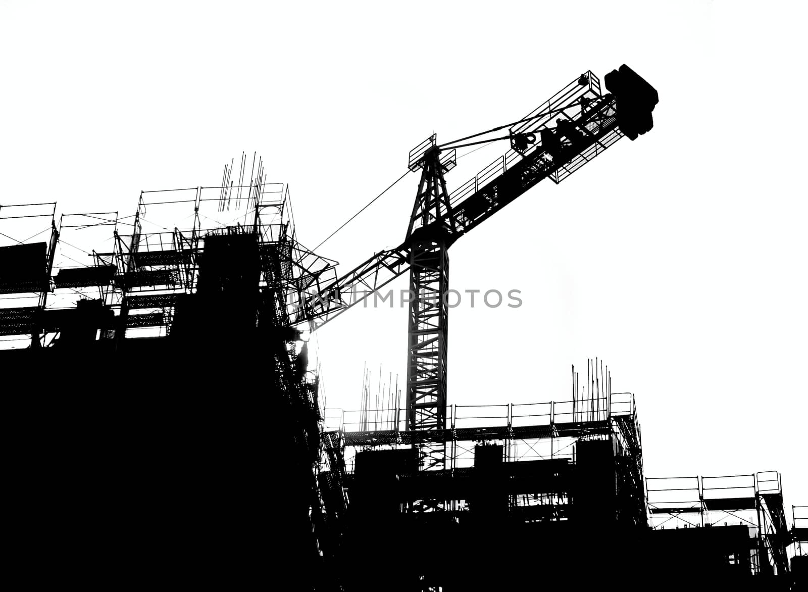 Construction site with crane and scaffolding seen as a silhouette