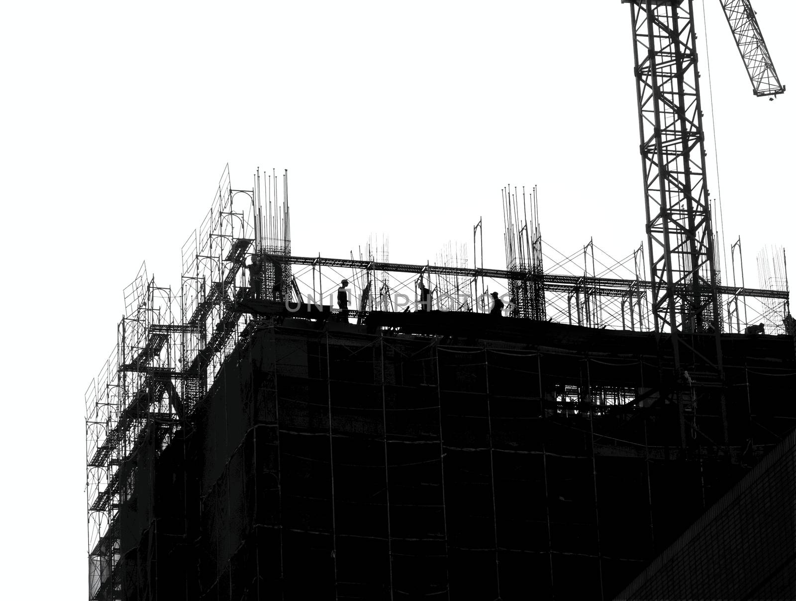 Construction site with crane and scaffolding seen as a silhouette