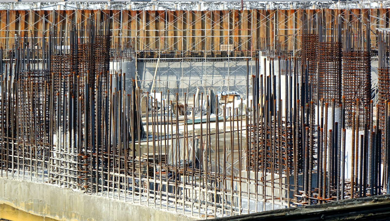 A large scale construction site with steel bars and concrete pillars
