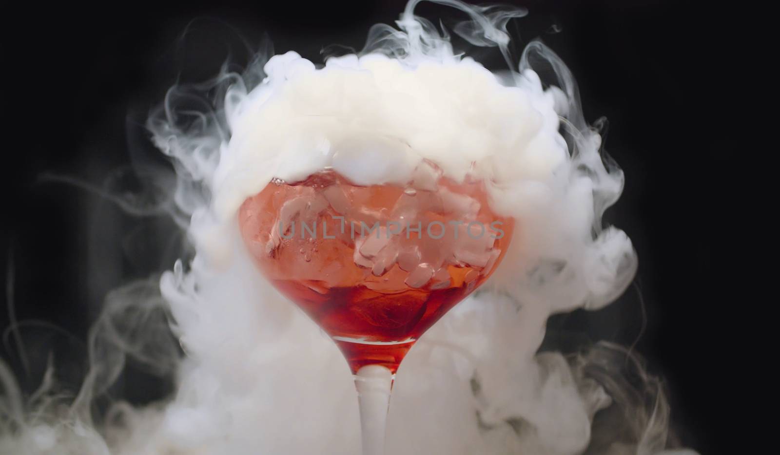 Close up glass of red cocktail with dry ice. The glass is wrapped in steam. Bar drinks and cocktails