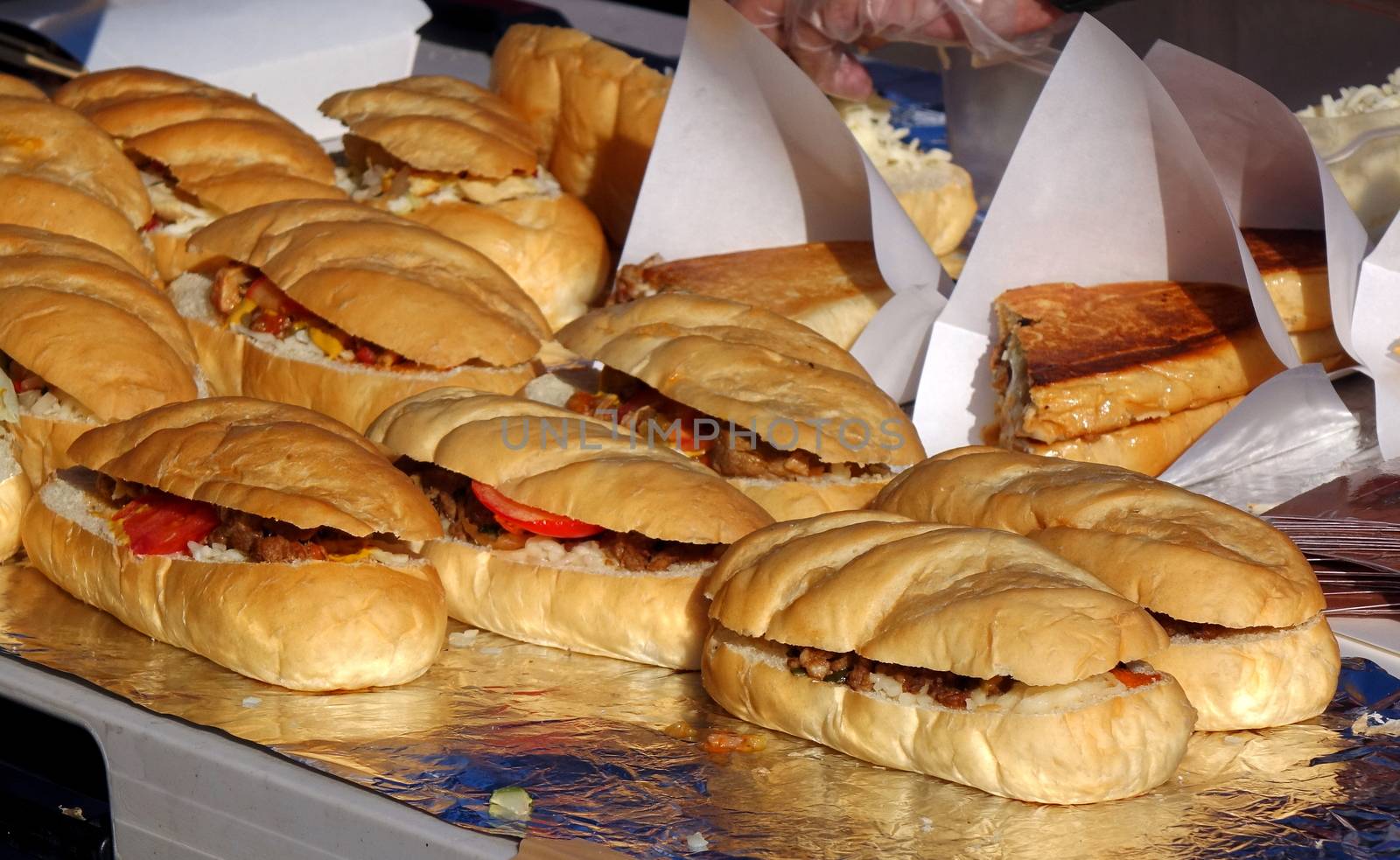 A street vendor sells sandwiches with roasted meat, tomatoes and pickles
