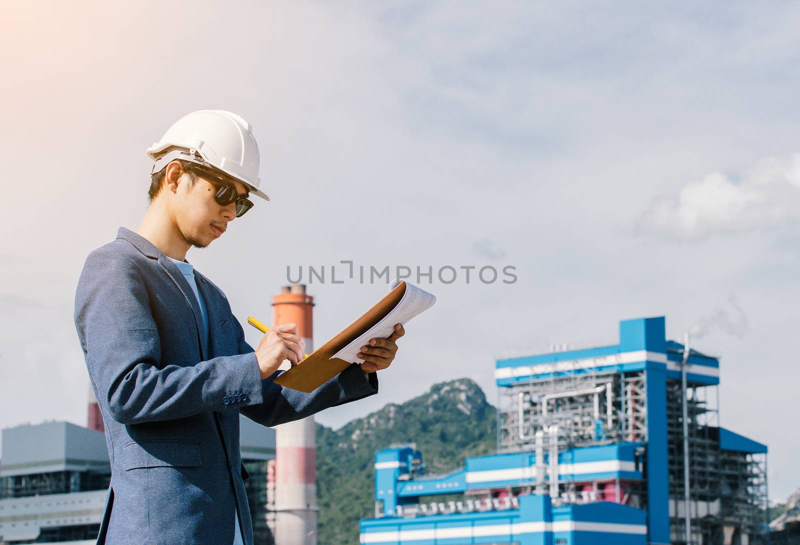 Engineer with a coal power plant in the background, Thailand