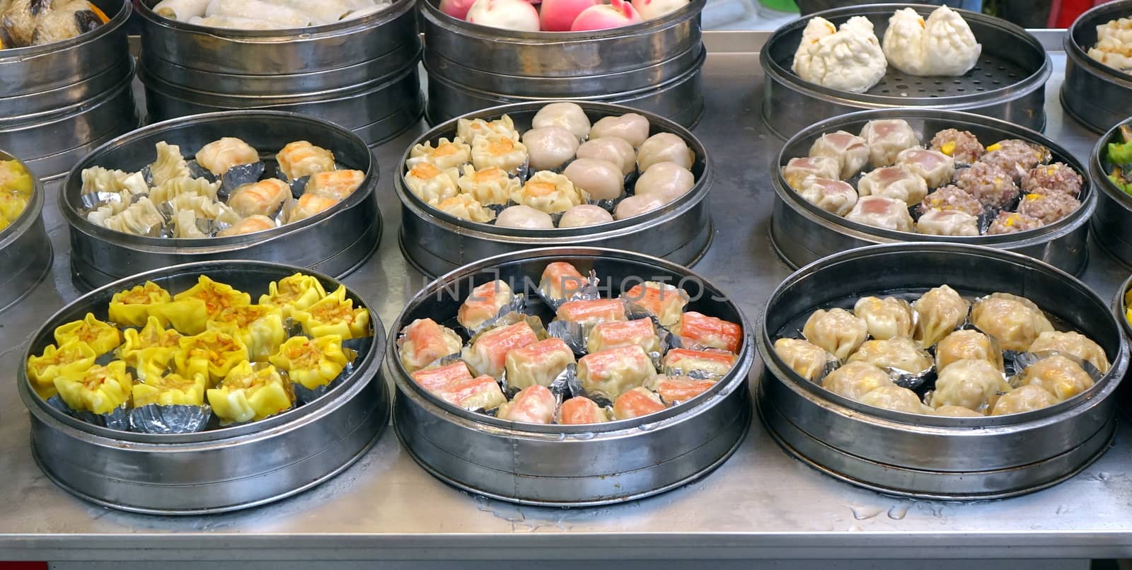 An outdoor vendor sells Cantonese Dim Sum dishes cooked in metal steamers