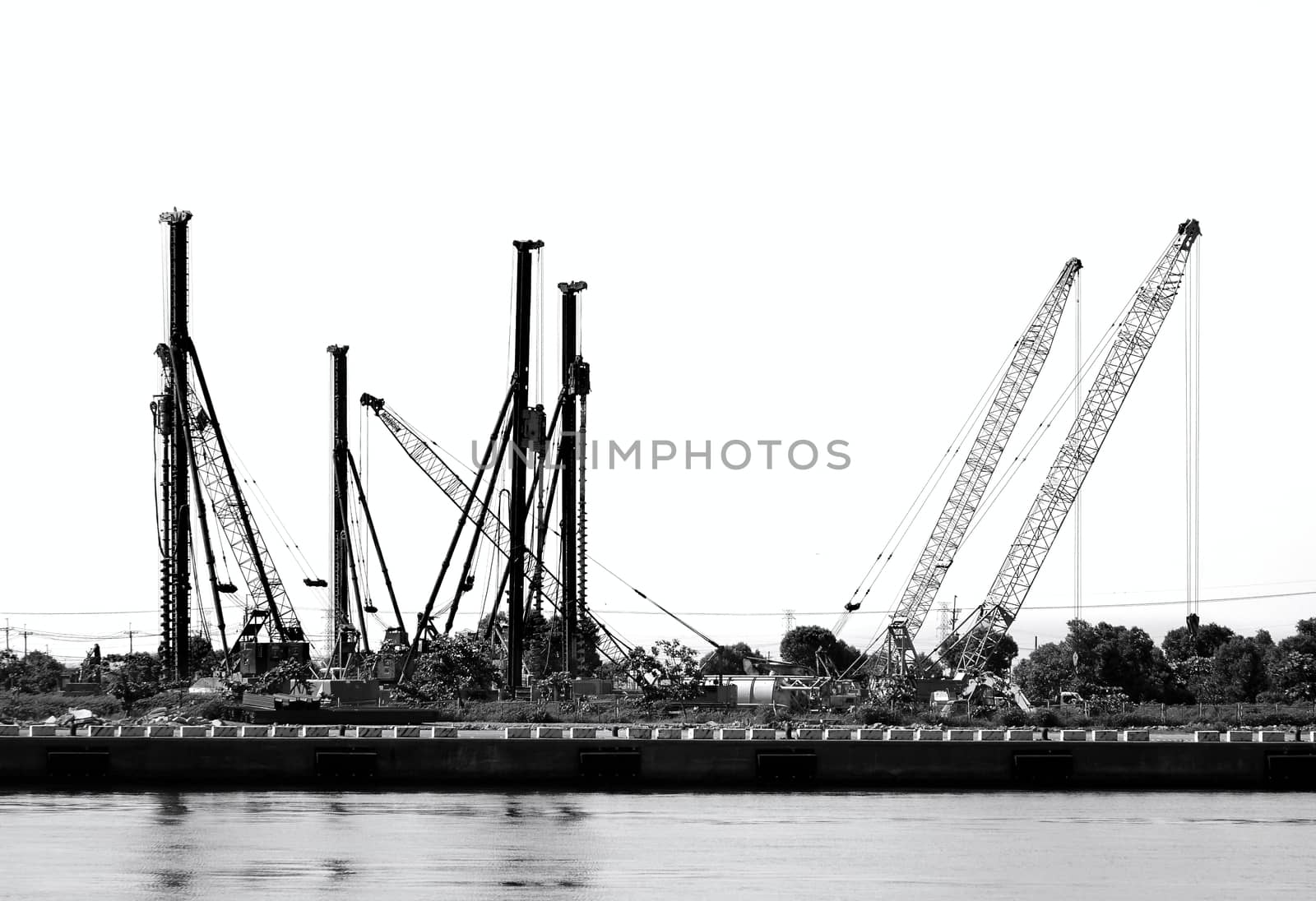 A construction site with drilling rigs and cranes seen in silhouette