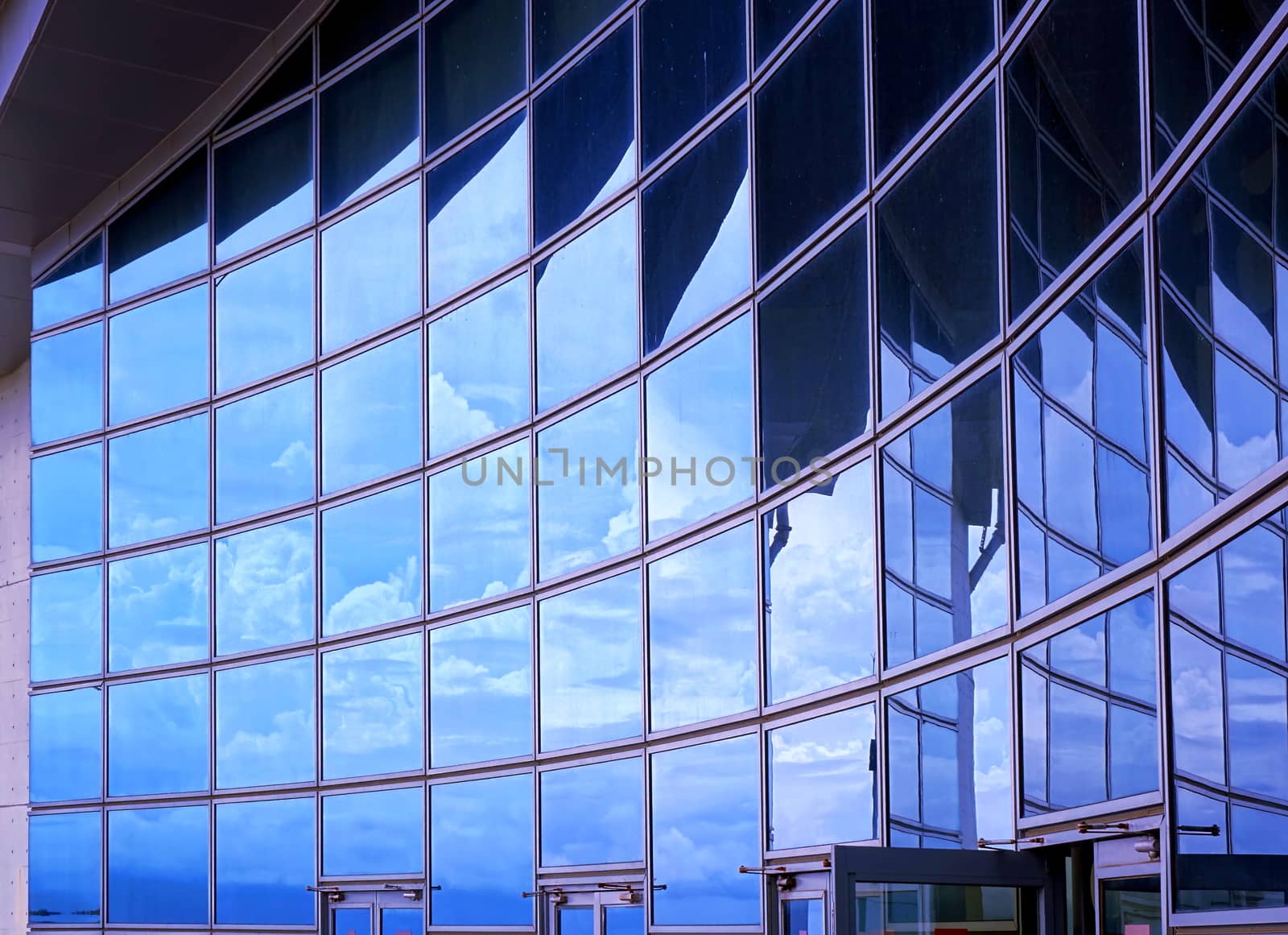A modern corporate building with a curved facade reflecting the sky
