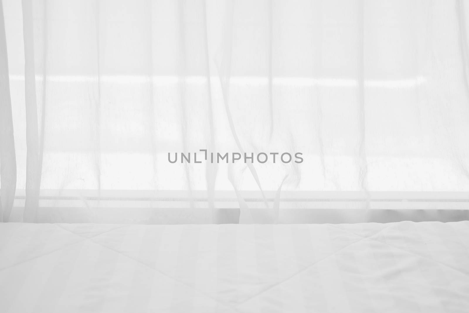 white mattress bed beside see through sheer window curtain