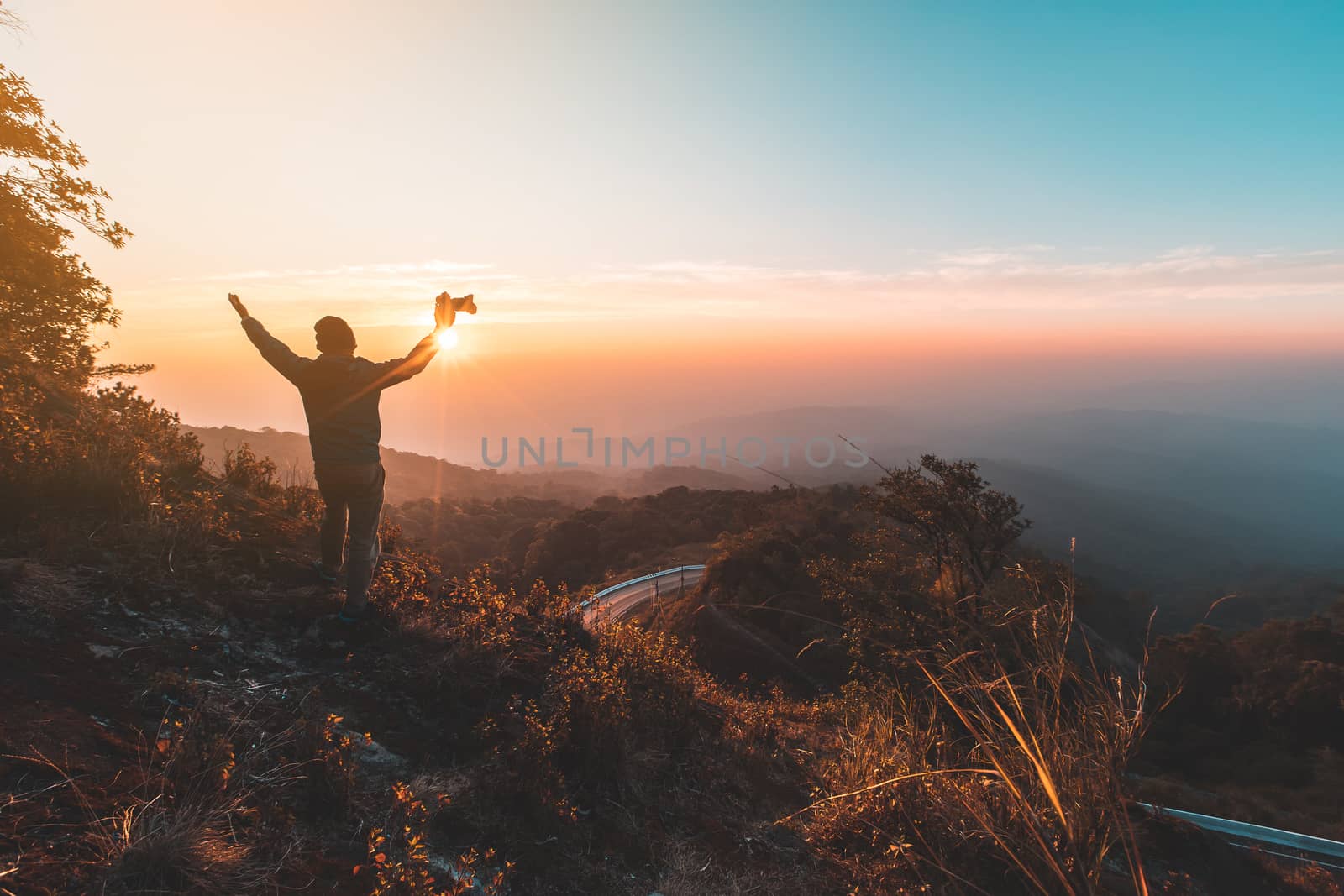 Silhouette of man hold up hands on the peak of mountain,success  by freedomnaruk