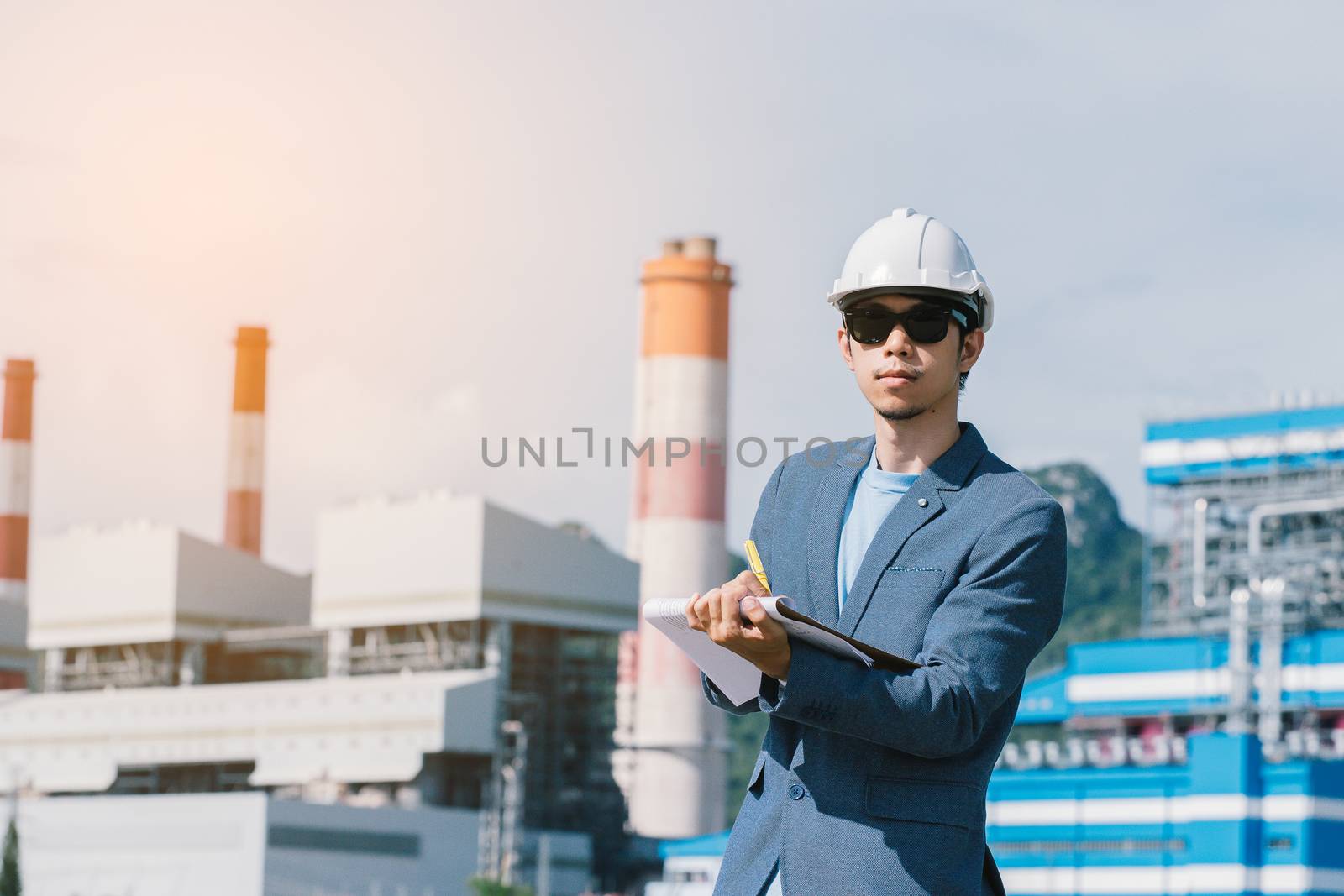 Engineer with a coal power plant in the background, Thailand