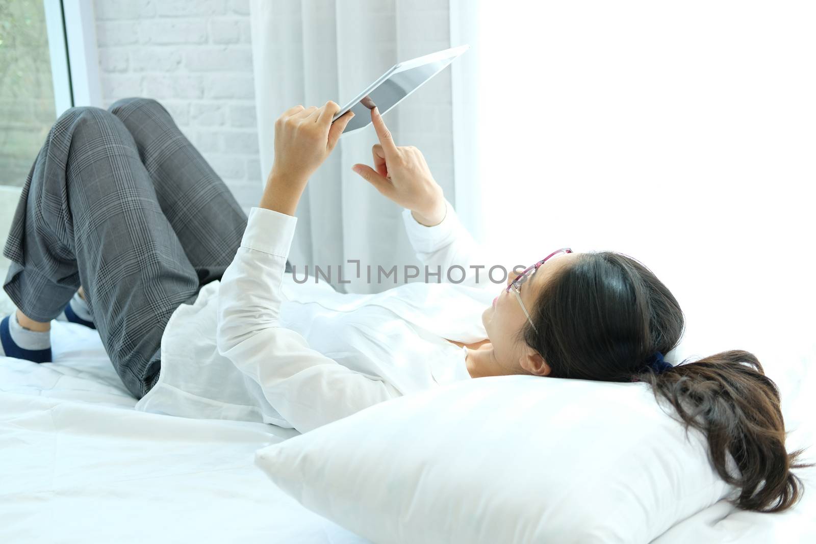 woman using tablet lying on bed at home by pp99