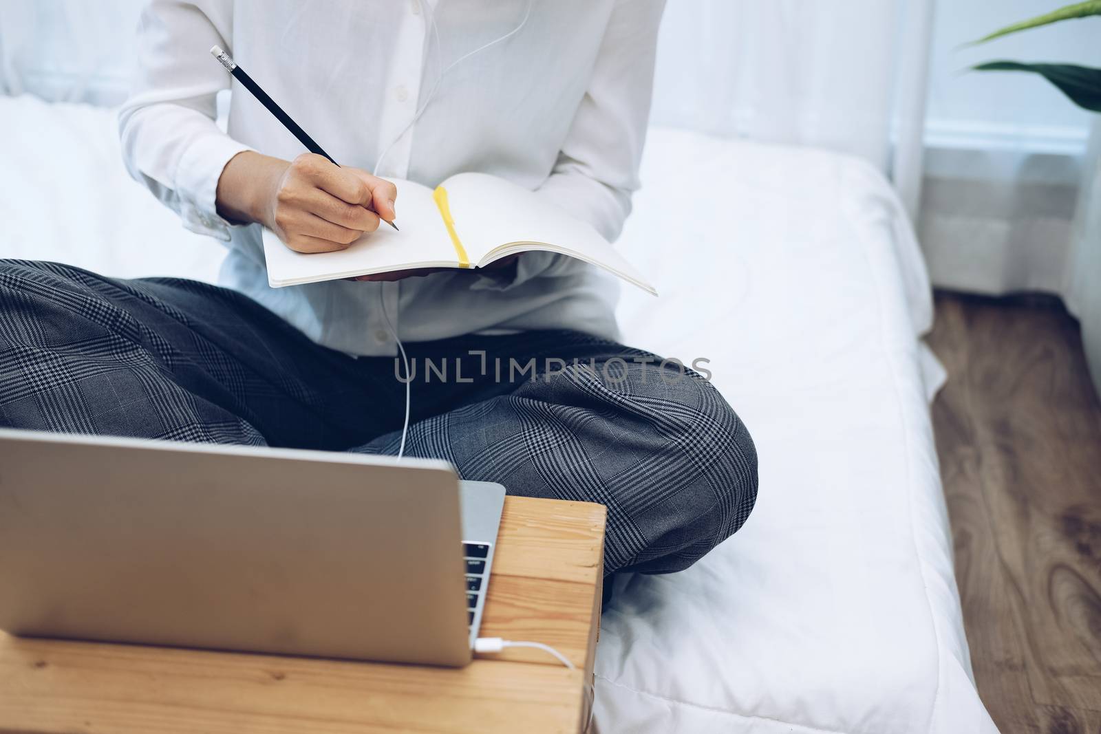 asian woman wearing earphones writing note watching video. student listen lecture study online course