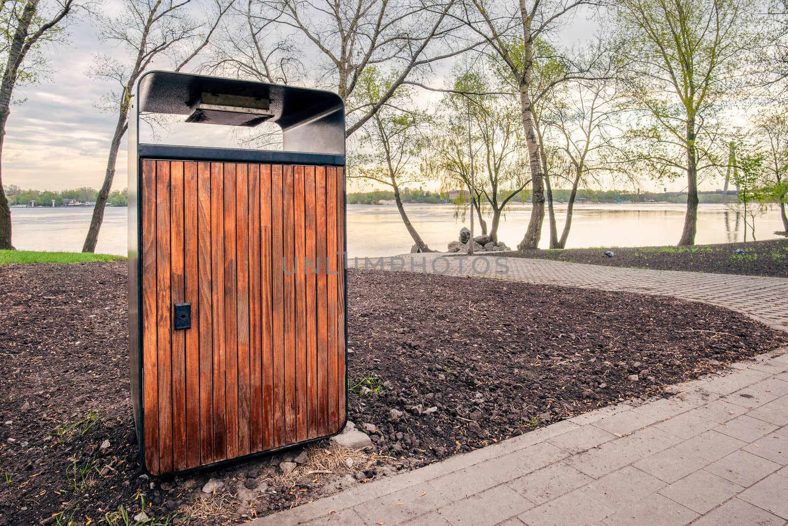 A wooden and metallic trash bin in the Natalka park of Kiev, Ukraine, close to the Dnieper river in spring