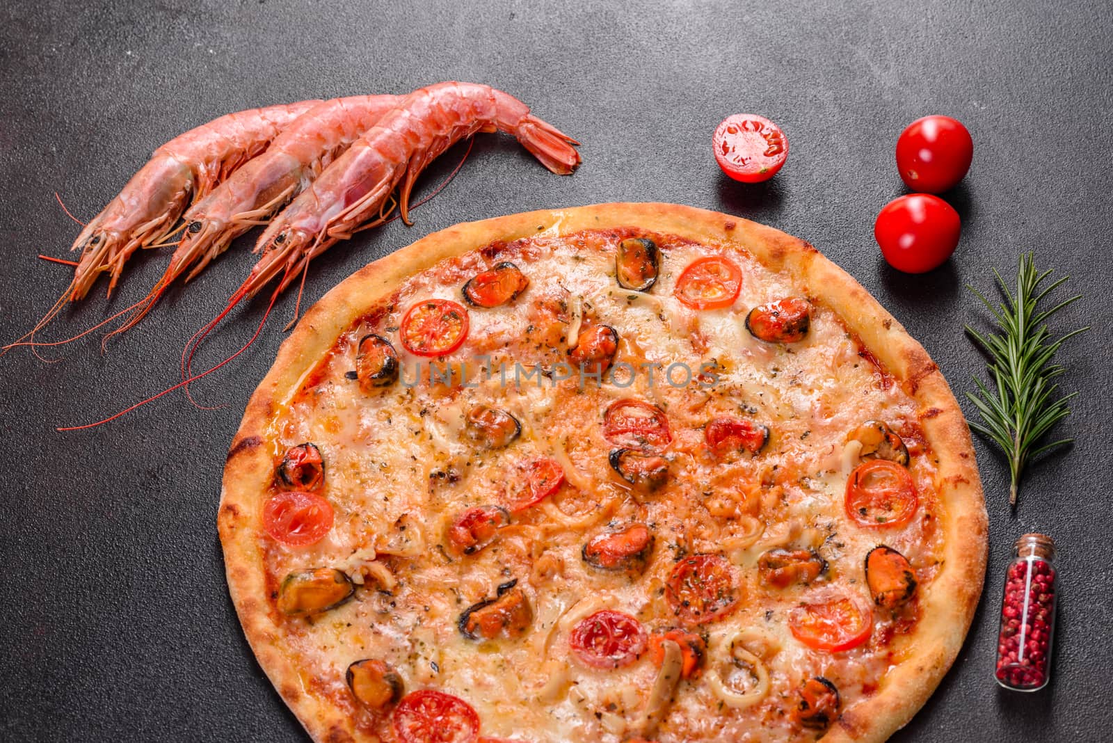 Seafood Italian pizza with shrimp, squid, mussels, fresh herbs and mozzarella on a
dark background. Tasty sliced pizza with seafood and tomato on a concrete background