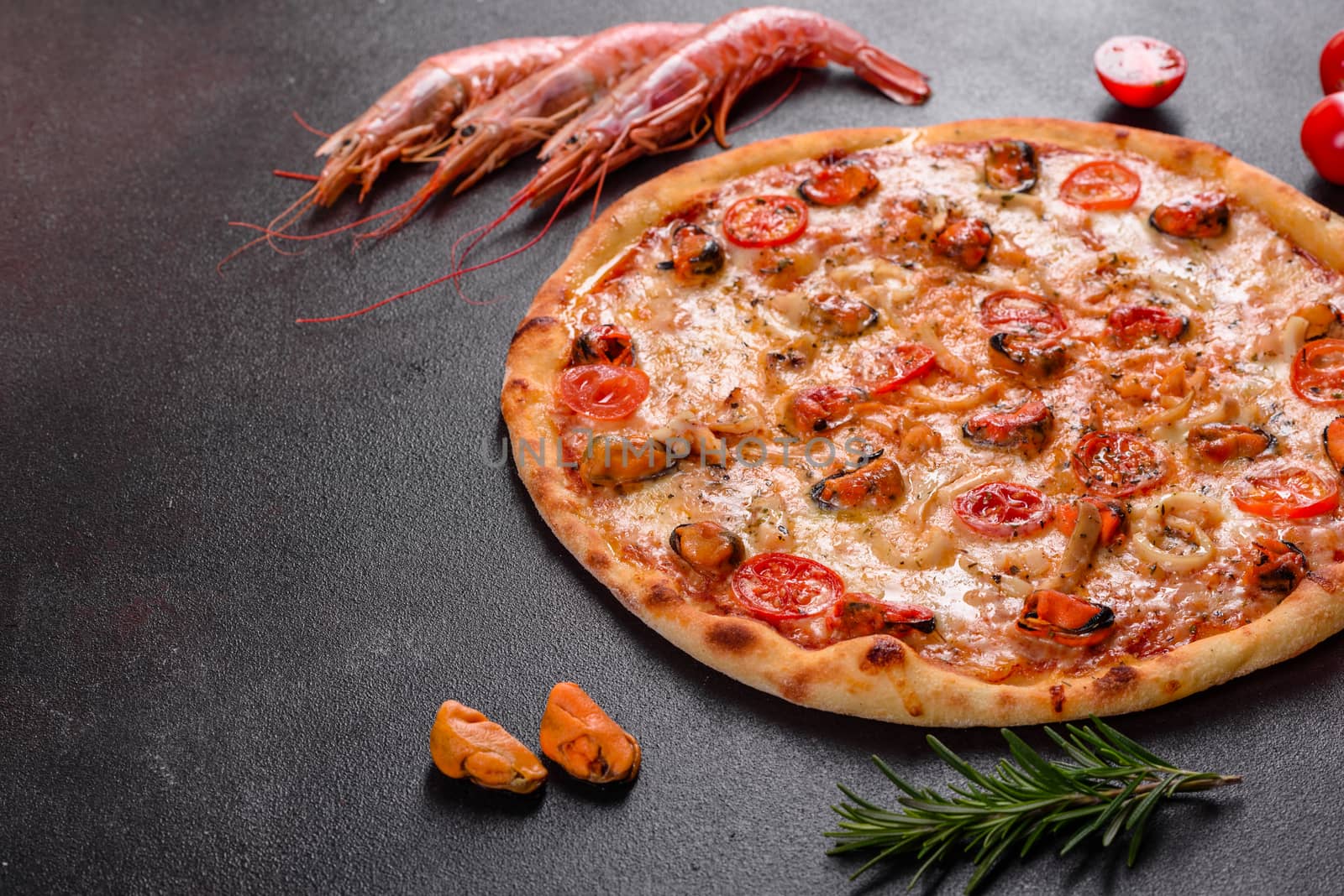 Seafood Italian pizza with shrimp, squid, mussels, fresh herbs and mozzarella on a
dark background. Tasty sliced pizza with seafood and tomato on a concrete background