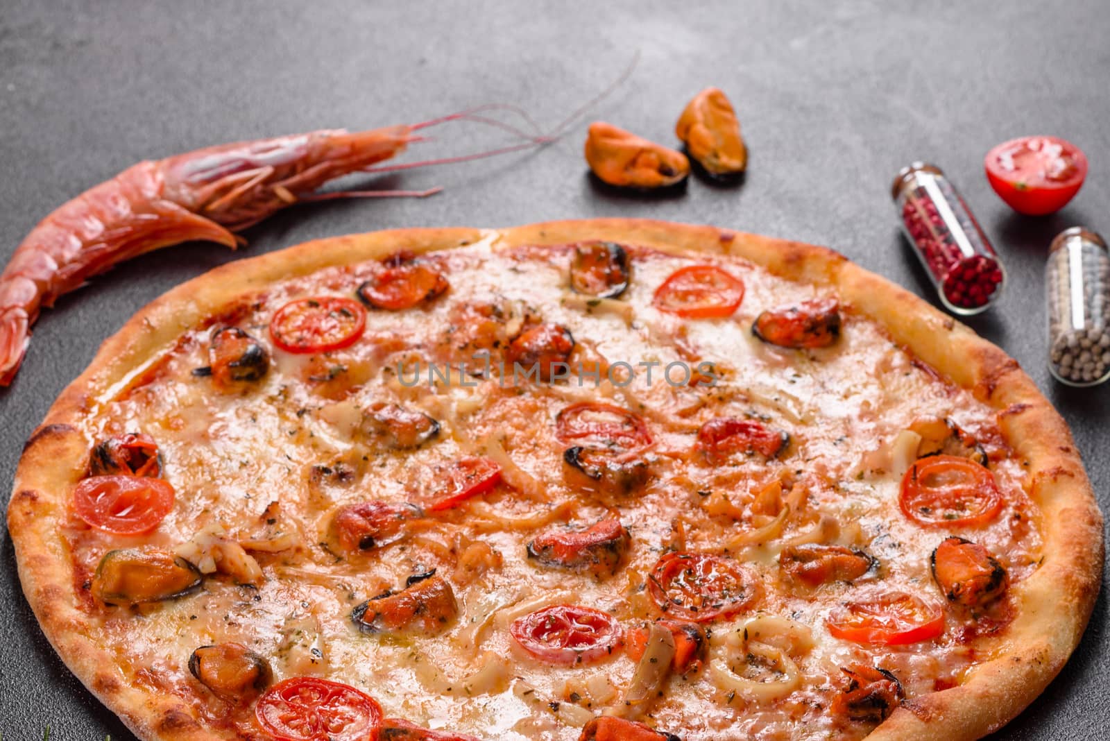Seafood Italian pizza with shrimp, squid, mussels, fresh herbs and mozzarella on a
dark background. Tasty sliced pizza with seafood and tomato on a concrete background